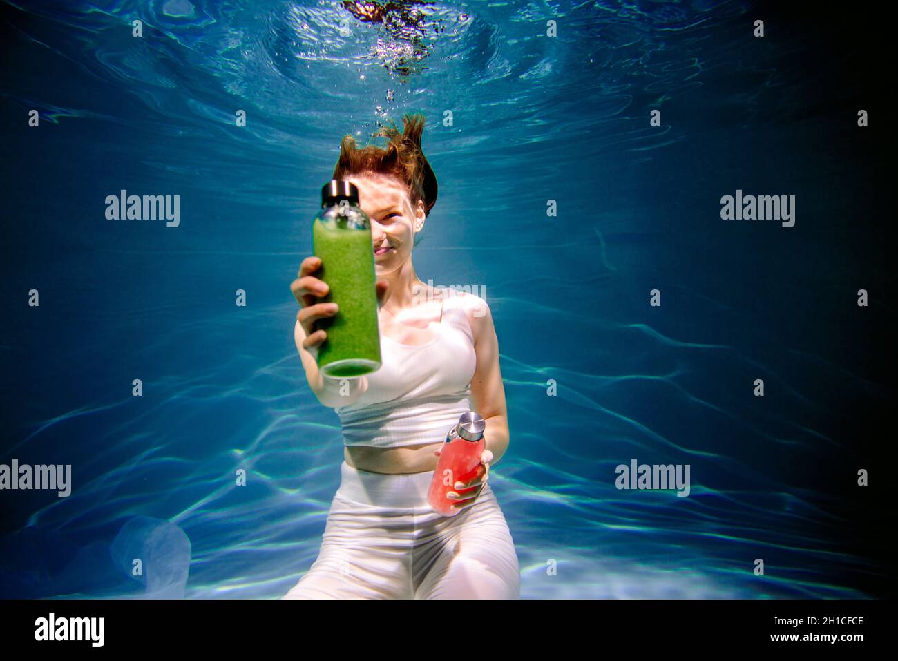 Fitness-Mädchen mit bunten Smoothie. Frische unter Wasser, schwimmt und taucht. Stockfoto