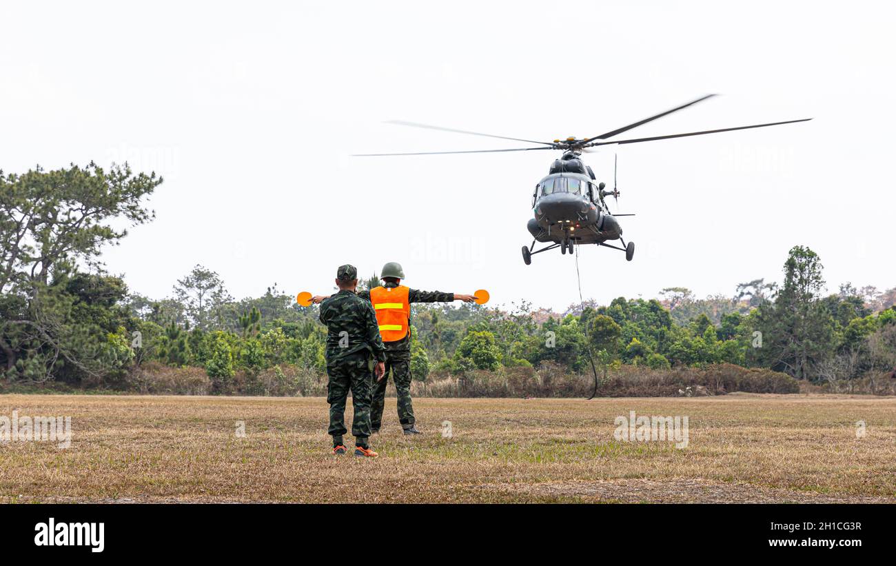 Zwei Soldaten, die auf dem Boden stehen, geben Signal und Richtung für die Sicherheit, um im schwimmenden Hubschrauber im Landebereich im Naturpark zu pilotieren. Stockfoto