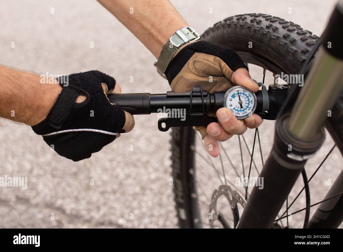 Mann, der den Reifendruck des E-Bikes überprüft und die Luft mit der Handpumpe aufpumpt Stockfoto