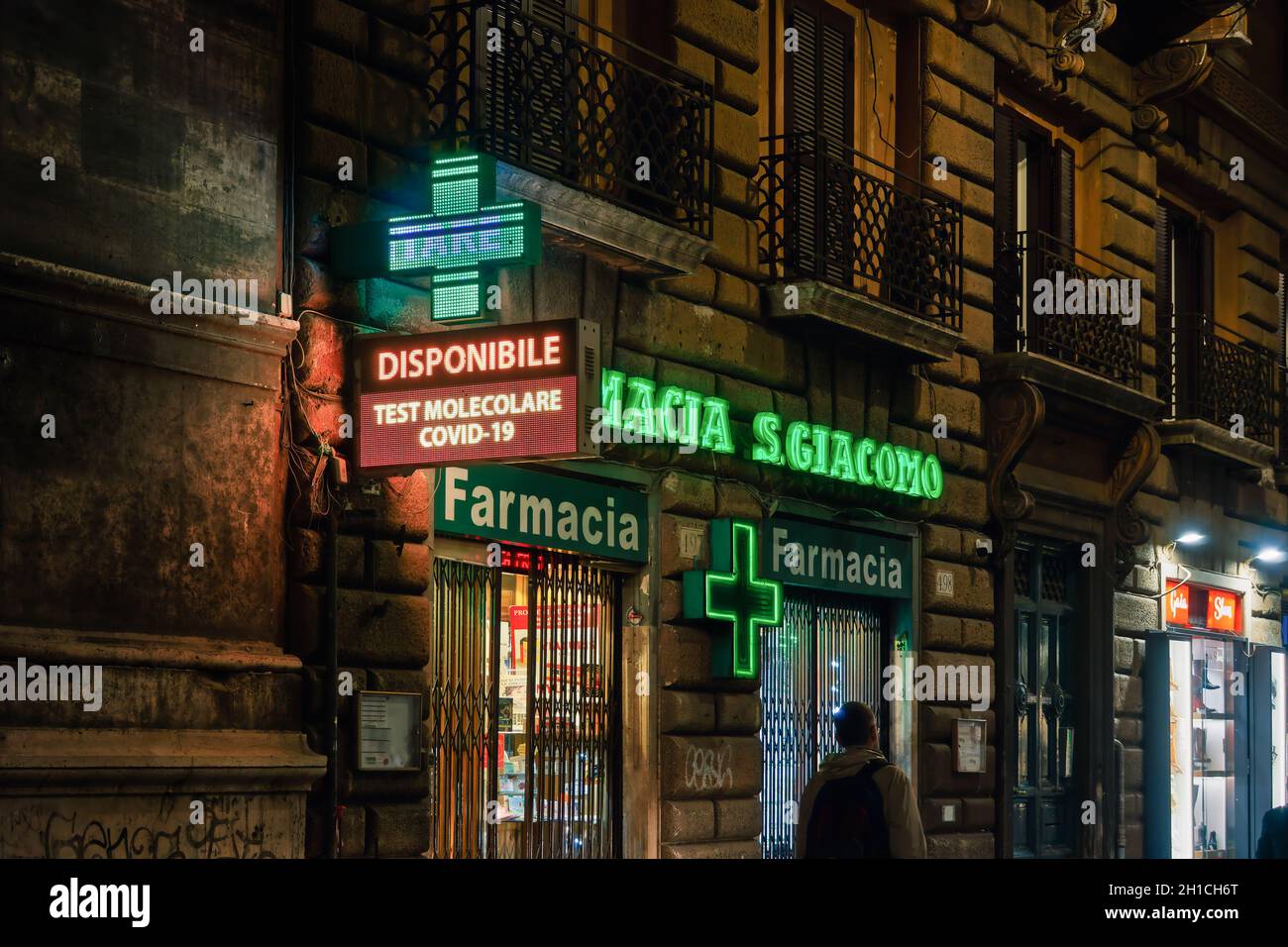 Rom, Italien Öffnen Sie den Eingang des Apotheken-Geschäfts mit dem Covid-19-Molekulartestschild. Außenansicht des italienischen Pharmazeutikladens mit beleuchtetem grünen Display und Schaufenster. Stockfoto