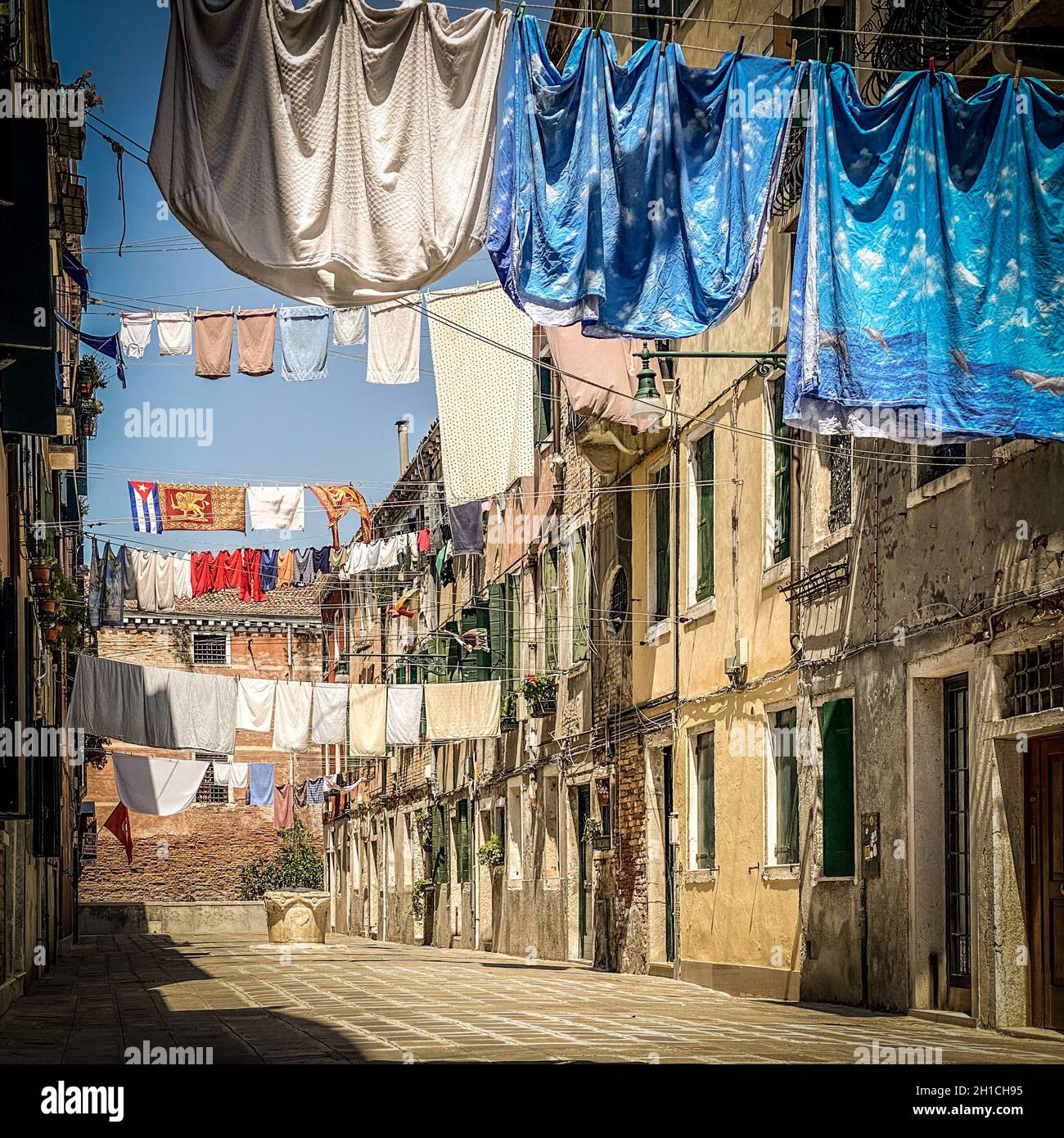 Hängende Kleidung, die auf einer kleinen traditionellen Straße in Venedig, Italien, zum Trocknen gebracht wird. Reisehintergrund Stockfoto