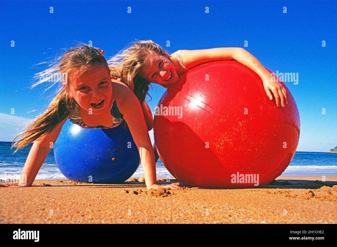 Kinder. Zwei Mädchen am Strand spielen mit aufblasbaren Strandbällen. Stockfoto