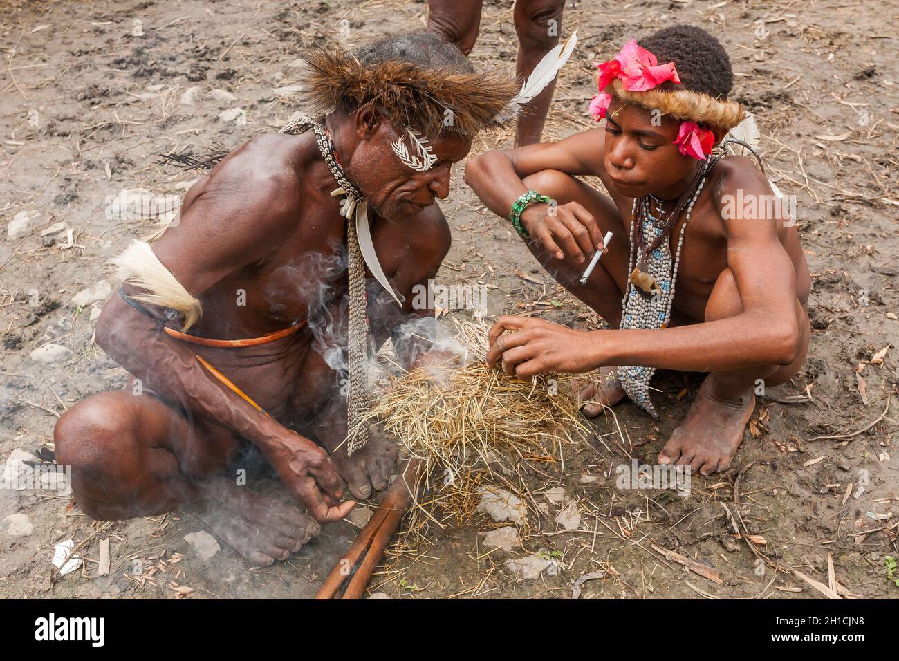 Wamena, Indonesien - 9. Januar 2010: Männer des Dani-Stammes in traditioneller Kleidung, die Feuer anzünden. Indonesisch-Neuguinea Stockfoto