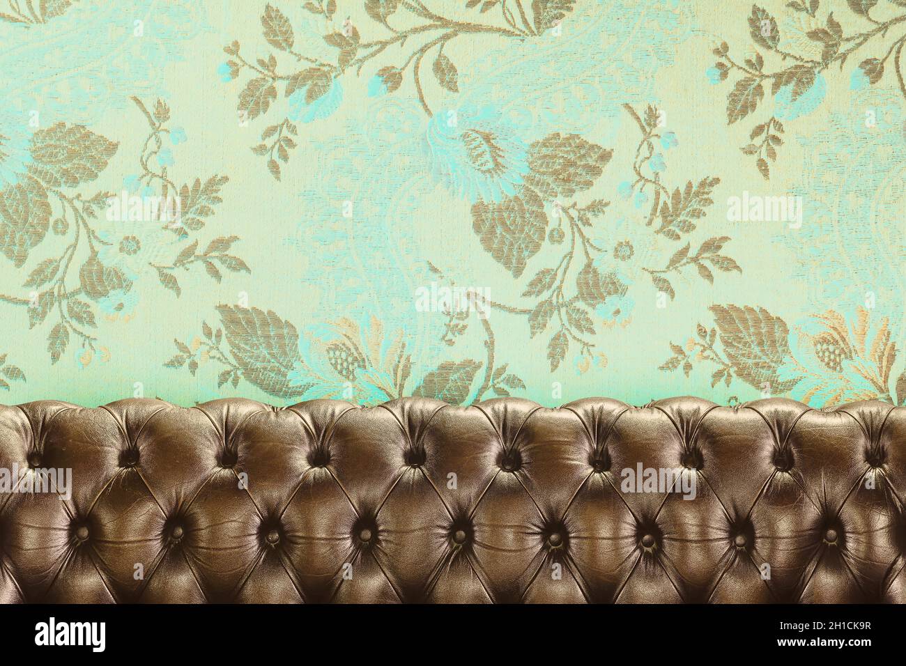 Retro-Stil Bild eines alten chesterfield Sofa vor der Tapete mit einem floralen Muster Stockfoto