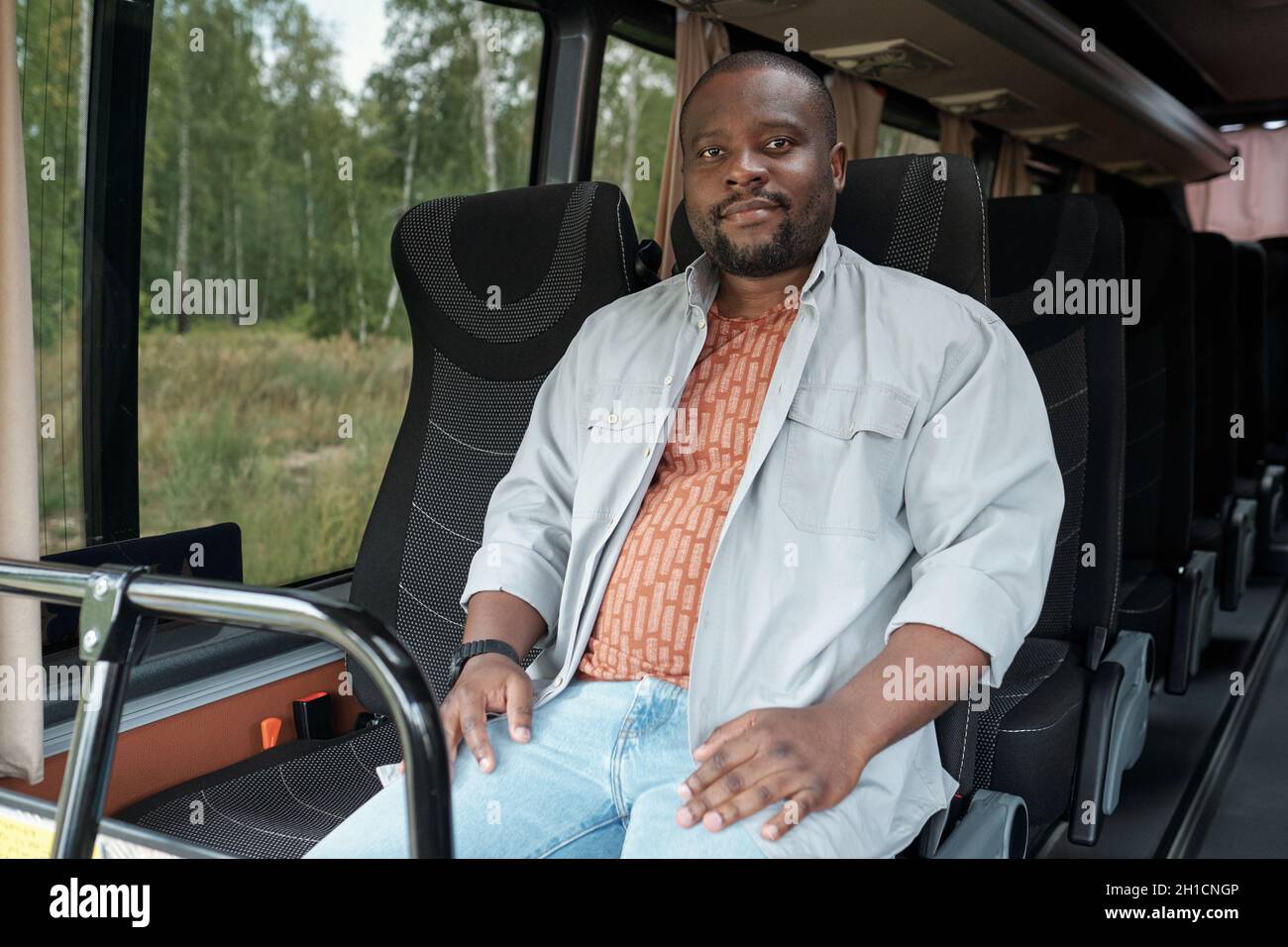 Junger, zeitgenössischer afrikanischer Mann, der auf dem vorderen Doppelsitz sitzt, während er im Intercity-Bus fährt Stockfoto