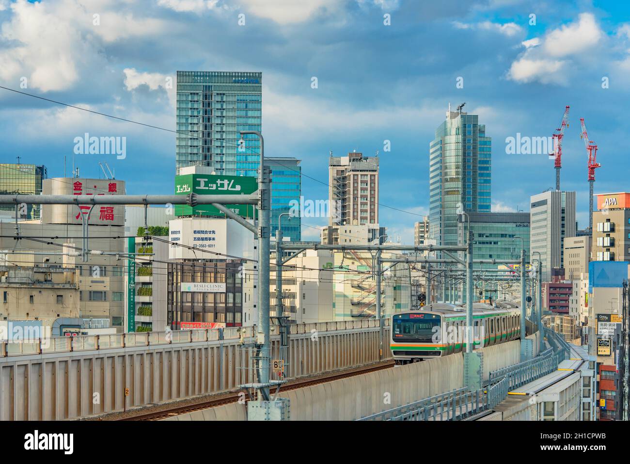 kanda-Bahnhof, an dem die Züge der yamanote-Linie unter dem blauen Himmel Tokios zwischen den Gebäuden des Bezirks Chiyoda fahren. Stockfoto