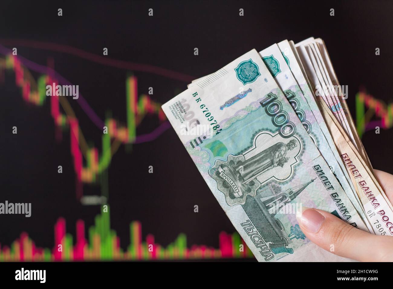 Hände, die russische Rubel vor einem Computermonitor mit Währungsmarkt und Forex-Handelskarte halten. Trading Stocks, Obligationen und Wertpapiere auf Stockfoto