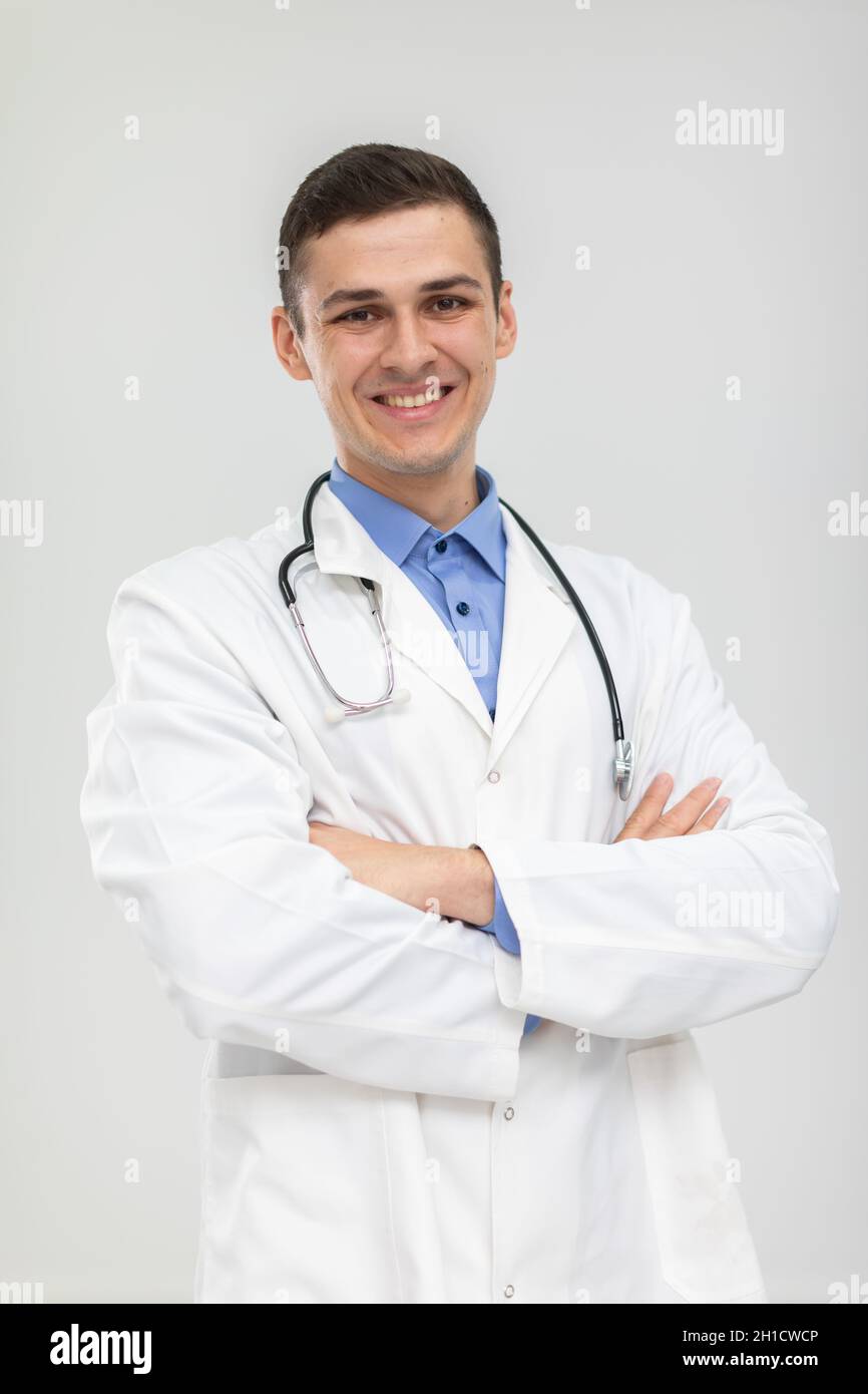 Der lächelnde Arzt steht mit gefalteten Händen in einem sanften Lächeln nach vorne. Stockfoto