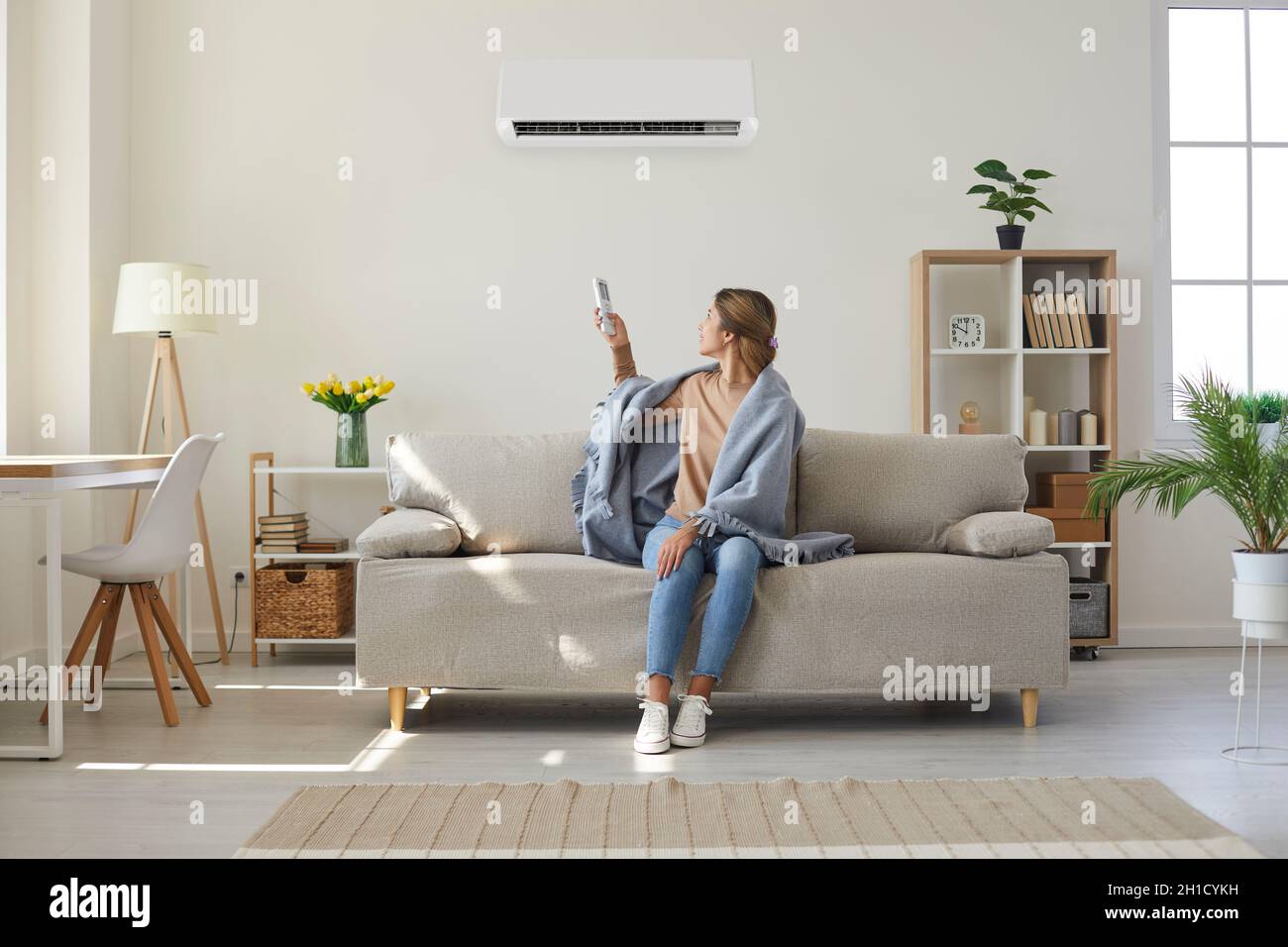 Frau genießt kühle frische Luft in ihrem Wohnzimmer mit Klimaanlage an der Wand Stockfoto
