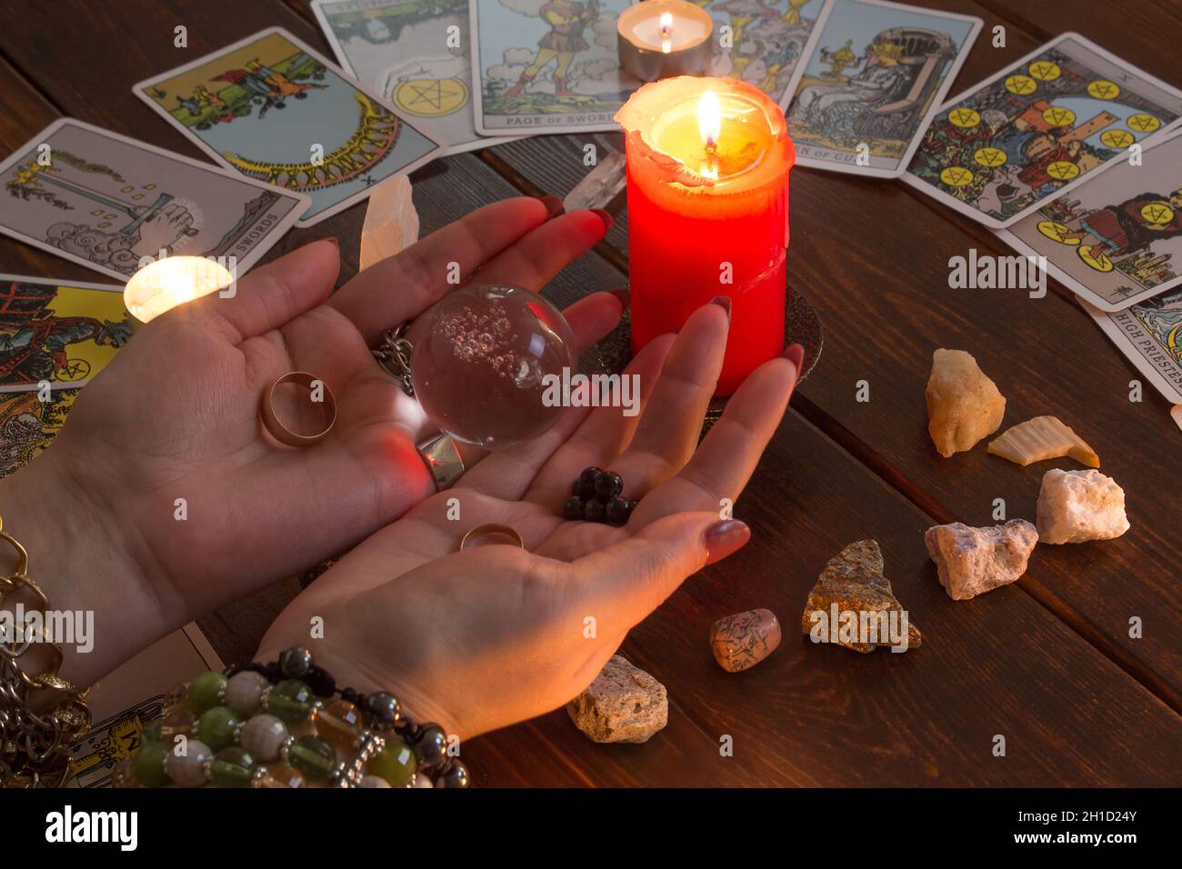 Bangkok, Thailand, März.15.20.das Mädchen hält Trauringe auf der Hand mit Tarot-Karten mit Herz, Kristallen, einem Zauberball und einer beleuchteten Kerze.Fortune t Stockfoto