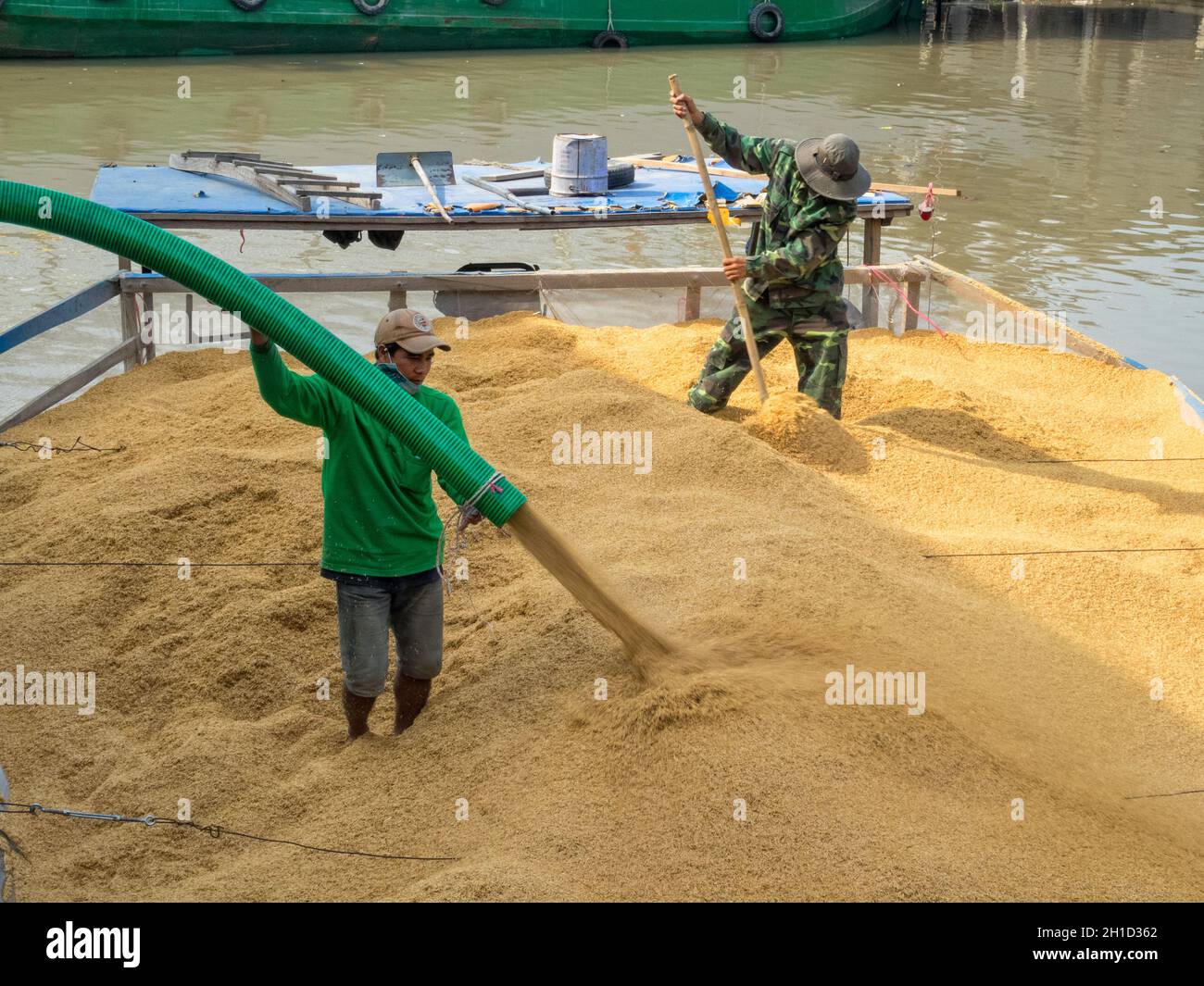 Zwei Arbeiter laden Reis auf einen BPAT im Mekong-Flussdelta - Phong Dien, Vietnam Stockfoto