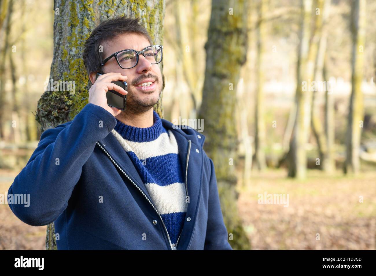 Lächelnder Mann, mit Handy in einem Herbstpark telefonieren. Stockfoto