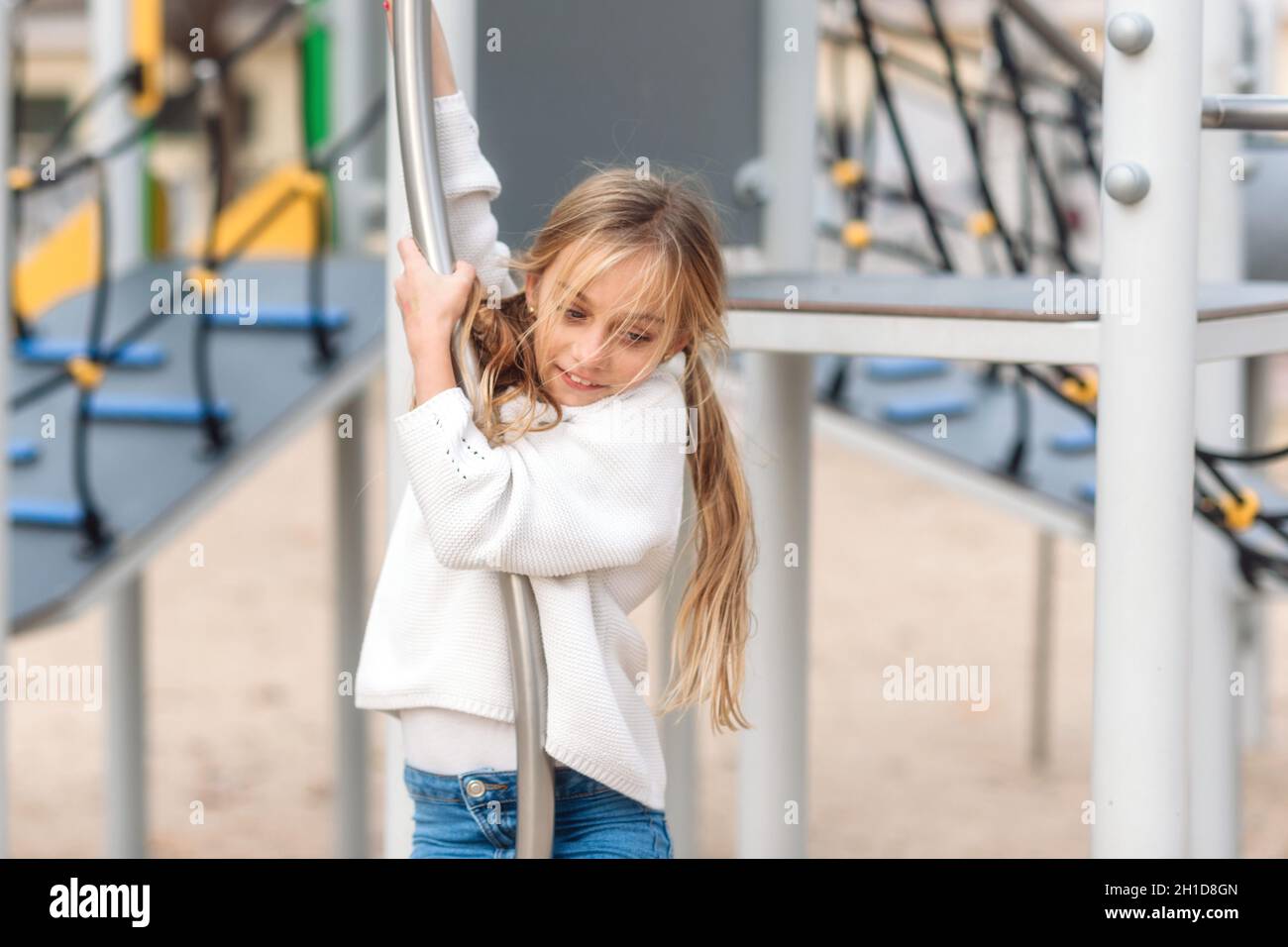 Hübsches, kleines Mädchen spielen auf Kinder spielplatz, bereit durch Pol zu schieben. Stockfoto