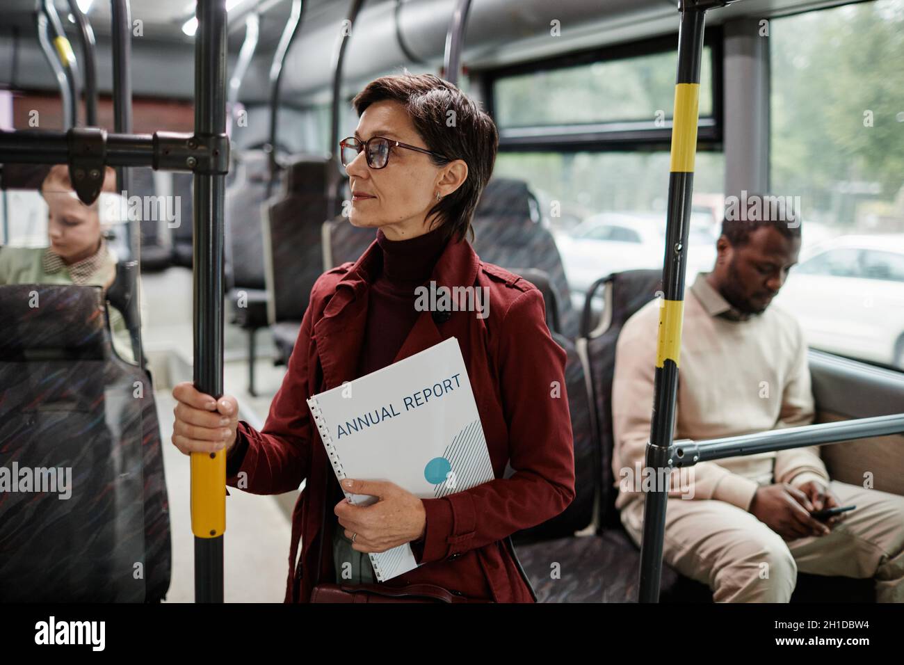 Seitenansicht Porträt einer eleganten erwachsenen Frau, die sich im Bus am Geländer festhält, während sie mit öffentlichen Verkehrsmitteln in der Stadt unterwegs ist, Kopierraum Stockfoto