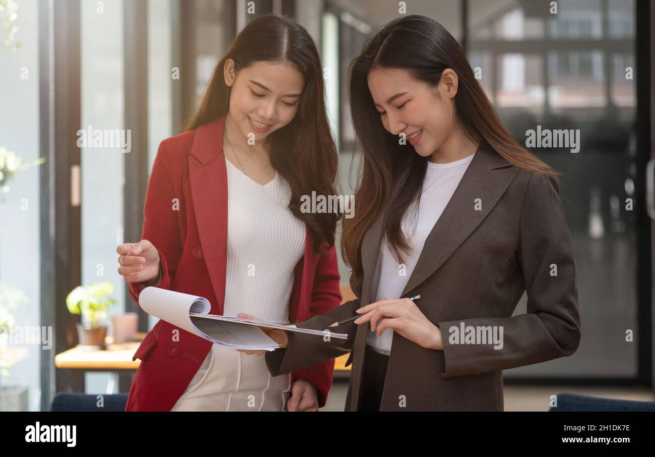 Zwei asiatische weibliche Kollegen stehen nebeneinander in einem Büro, Business Meeting Diskussionskonzept Stockfoto