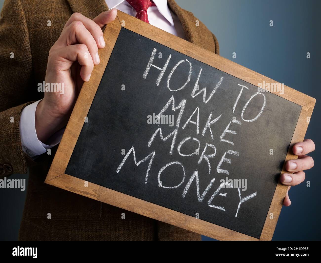 Berater hält Tafel mit Worten wie man mehr Geld verdient. Stockfoto