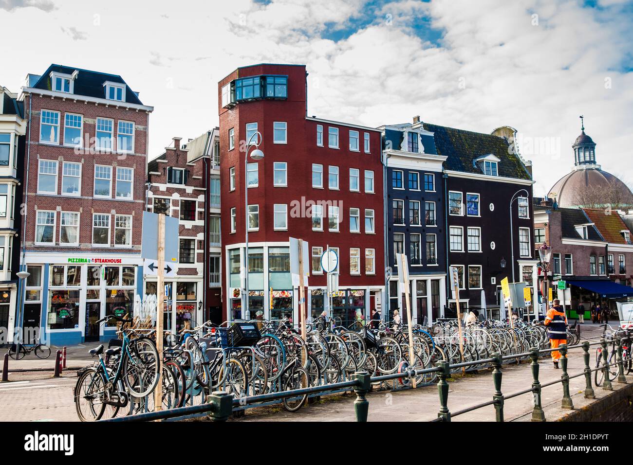 AMSTERDAM, NIEDERLANDE - MÄRZ, 2018: Wunderschöne Architektur und viele Fahrräder, die im Old Central District in Amsterdam geparkt sind Stockfoto