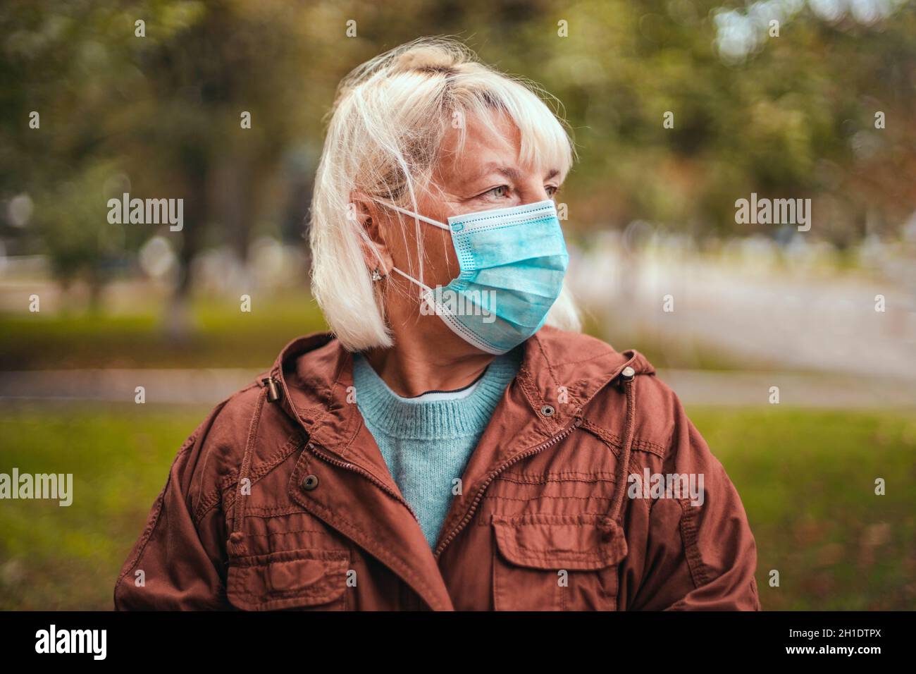 Frau trägt schützende Gesichtsmaske und in einem warmen Kaschmir Schal im Park im Freien während Quarantäne von Coronavirus Pandemie. Kopieren, leerer Platz für Text Stockfoto
