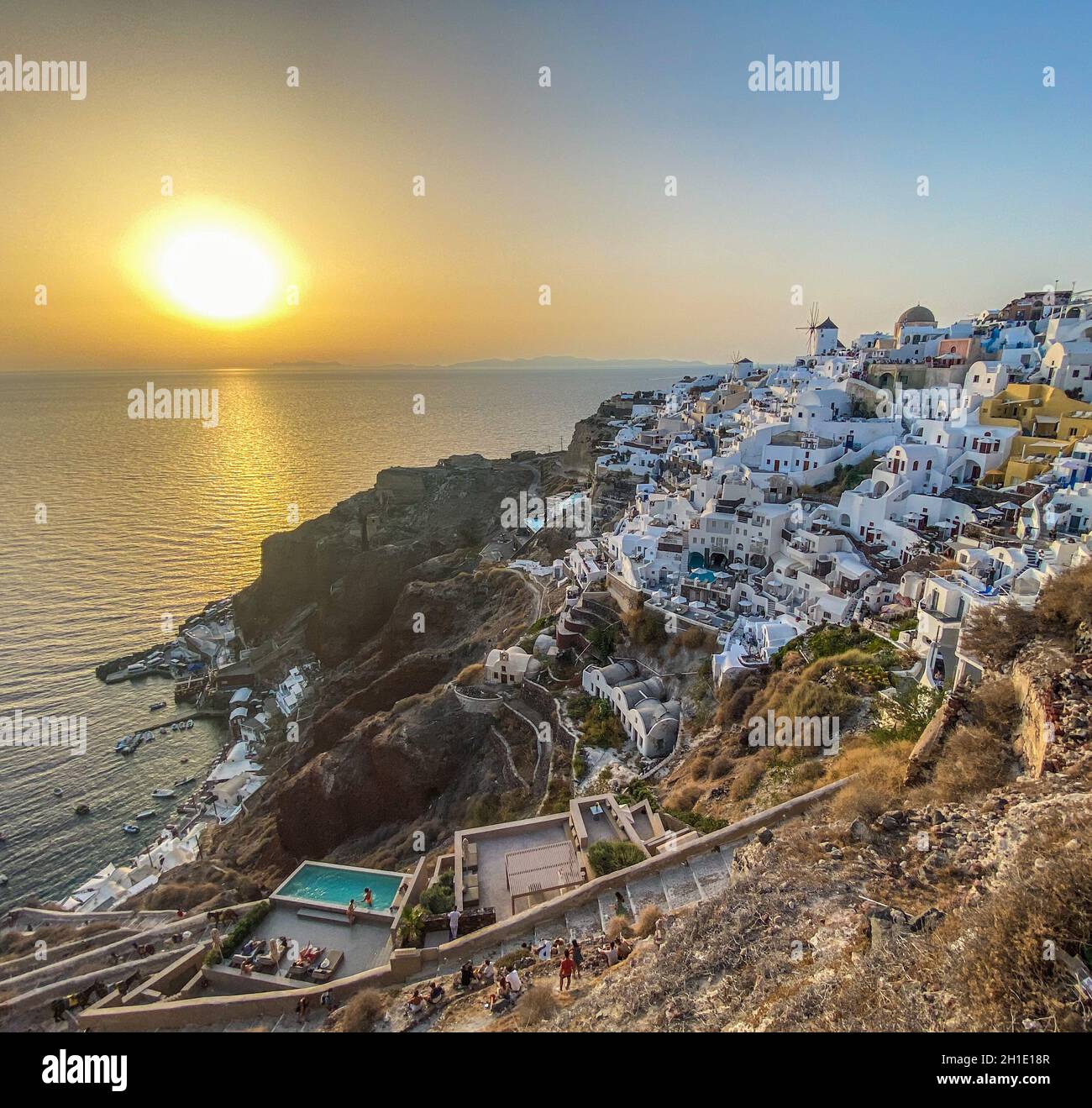 Panoramablick auf das Dorf Oia mit traditioneller weißer Architektur und Windmühlen auf der Insel Santorini in der Ägäis bei Sonnenuntergang, Reisehintergrund, Santor Stockfoto
