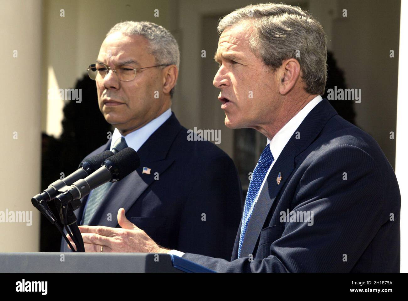 US-Präsident George W. Bush gibt am 4. April 2002 im Rosengarten des Weißen Hauses in Washington, DC, eine Ankündigung zu seiner Nahost-Politik ab, während US-Außenminister Colin Powell auf ihn schaut.Quelle: Ron Sachs / CNP/Sipa USA Stockfoto
