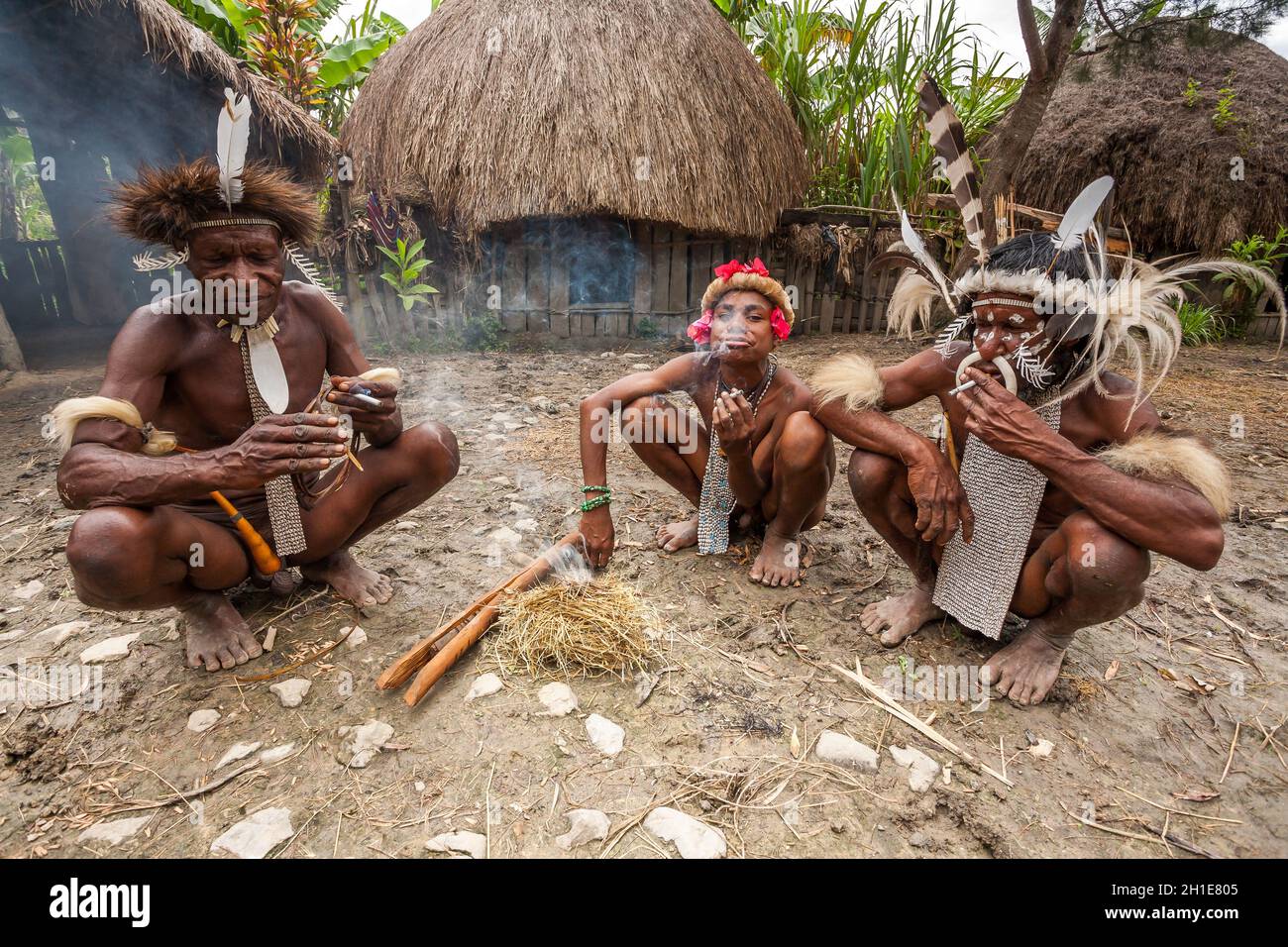Wamena, Indonesien - 9. Januar 2010: Drei Männer des Dani-Stammes in traditioneller Kleidung rauchen eine Zigarette Stockfoto