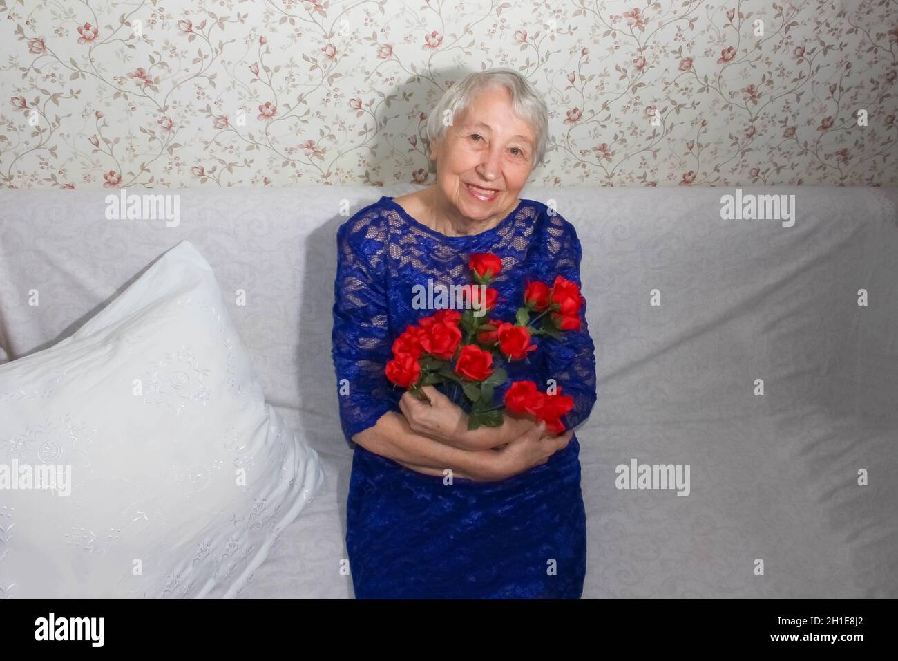 Porträt einer glücklichen Seniorin zu Hause mit Blumen Stockfoto