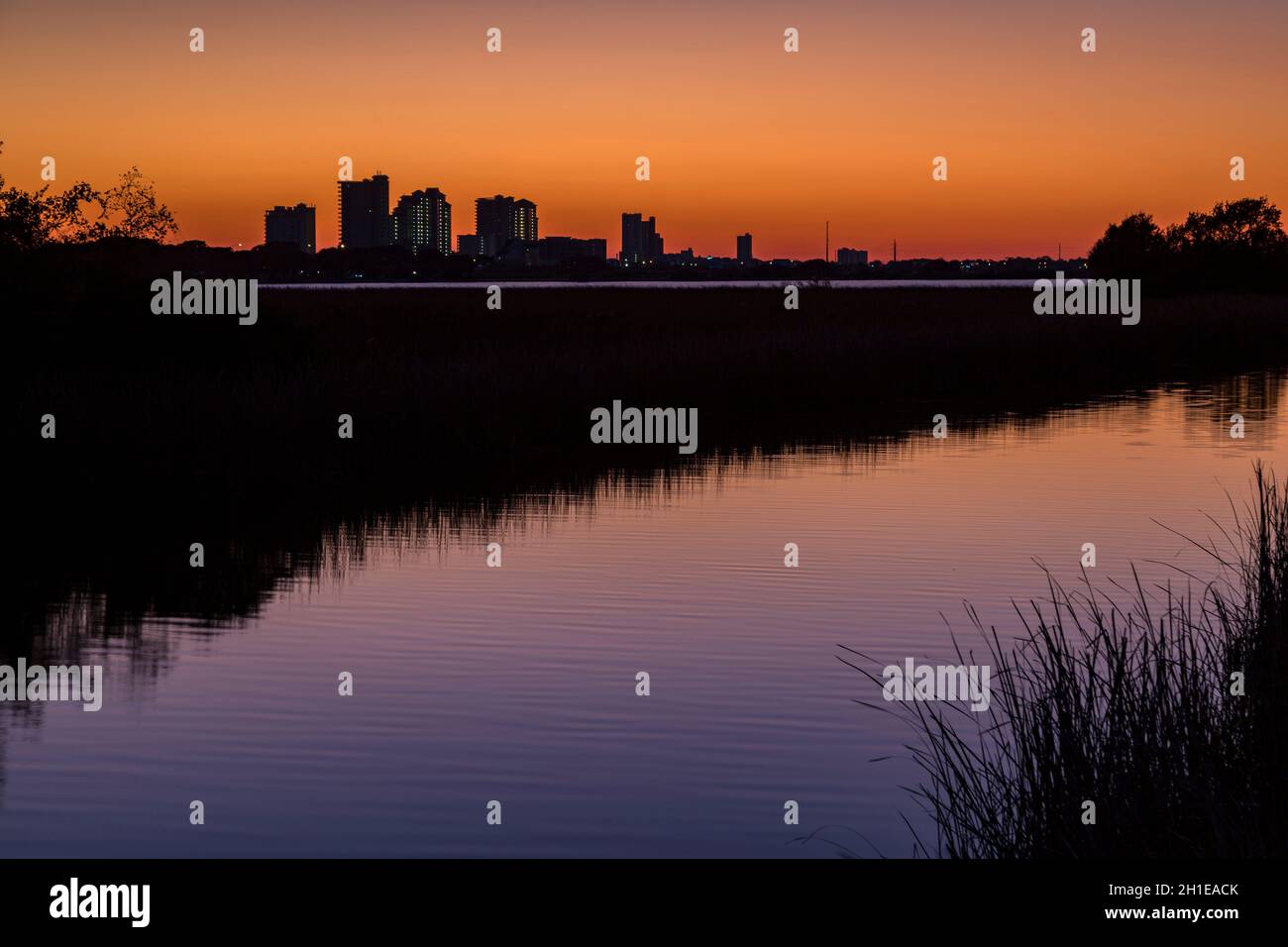 Silhouette der Hotels und Wohnanlagen von Gulf Shores, Alabama hinter dem Kanal nach Sonnenuntergang im Gulf State Park Stockfoto