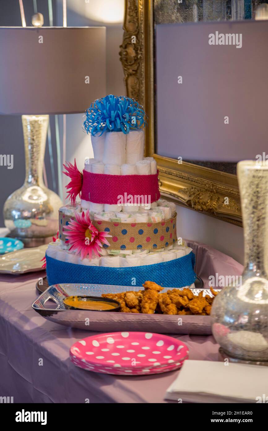 Babywindeln stapelten sich auf einer Geschlechtsparty zu einem Kuchen mit rosa und blauen Verzierungen Stockfoto