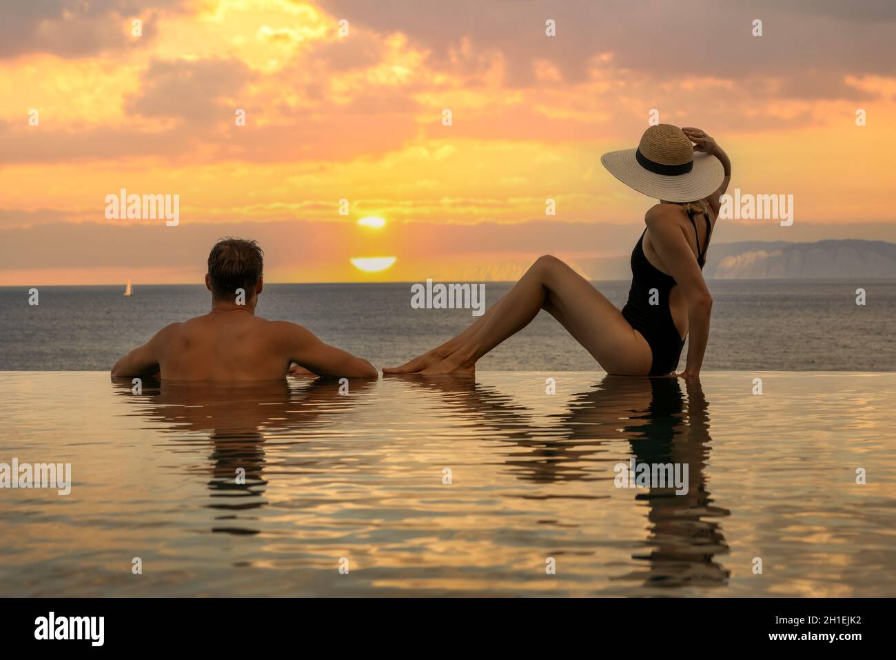 Hochzeitsreise - Pärchen genießen romantischen Sonnenuntergang im unendlichen Pool im Luxusresort Stockfoto