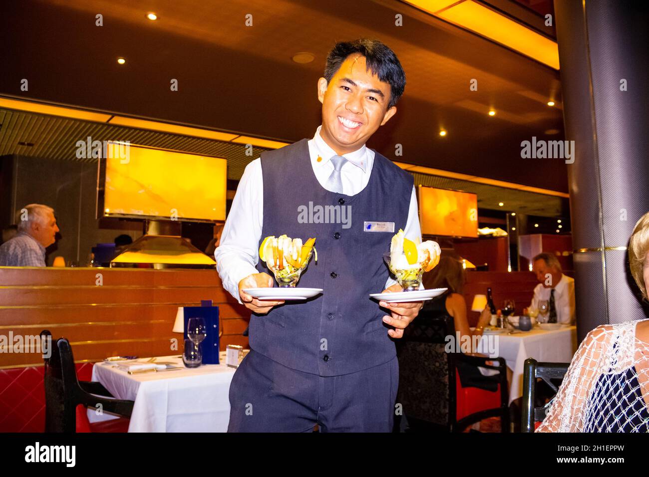 Willemstad, Curacao, Niederlande - 5. Dezember 2019: Der Kellner im Grande Restaurant und Tische mit Gerichten auf dem luxuriösen Holland America Kreuzfahrt-Schiff Euro Stockfoto