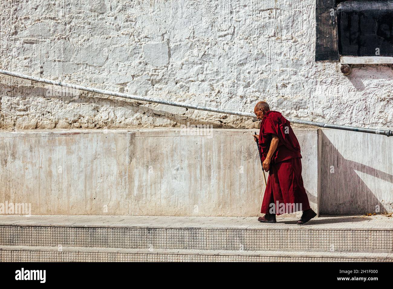 SPITUK, INDIEN - 15. SEPTEMBER 2012: Alter buddhistischer Mönch, der an der Wand von Spituk gompa, Ladakh, Indien, entlang geht Stockfoto