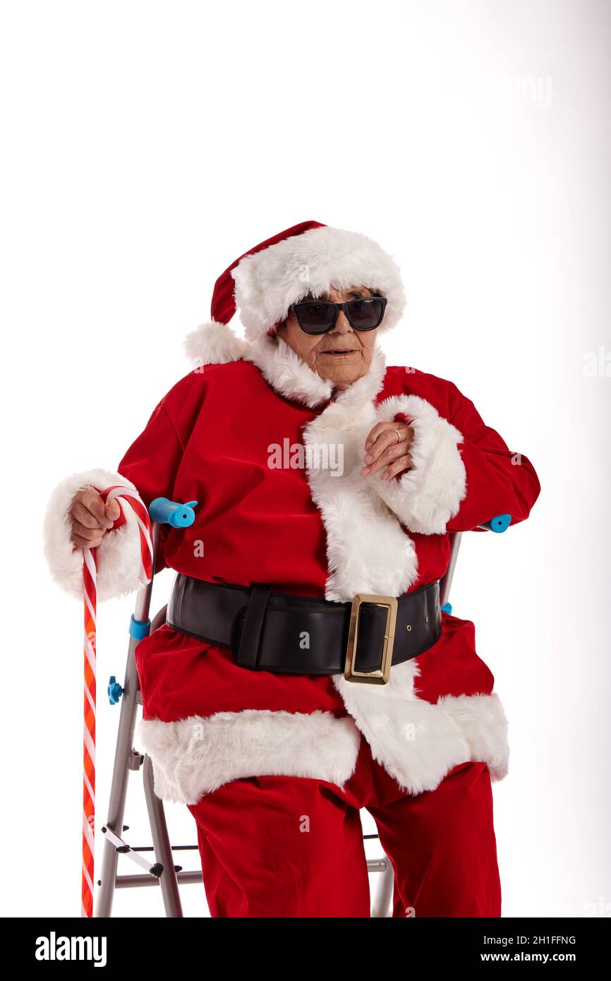 Eine ältere Frau, die als Weihnachtsmann gekleidet war, trug eine Sonnenbrille und schaute auf die Kamera. Stockfoto
