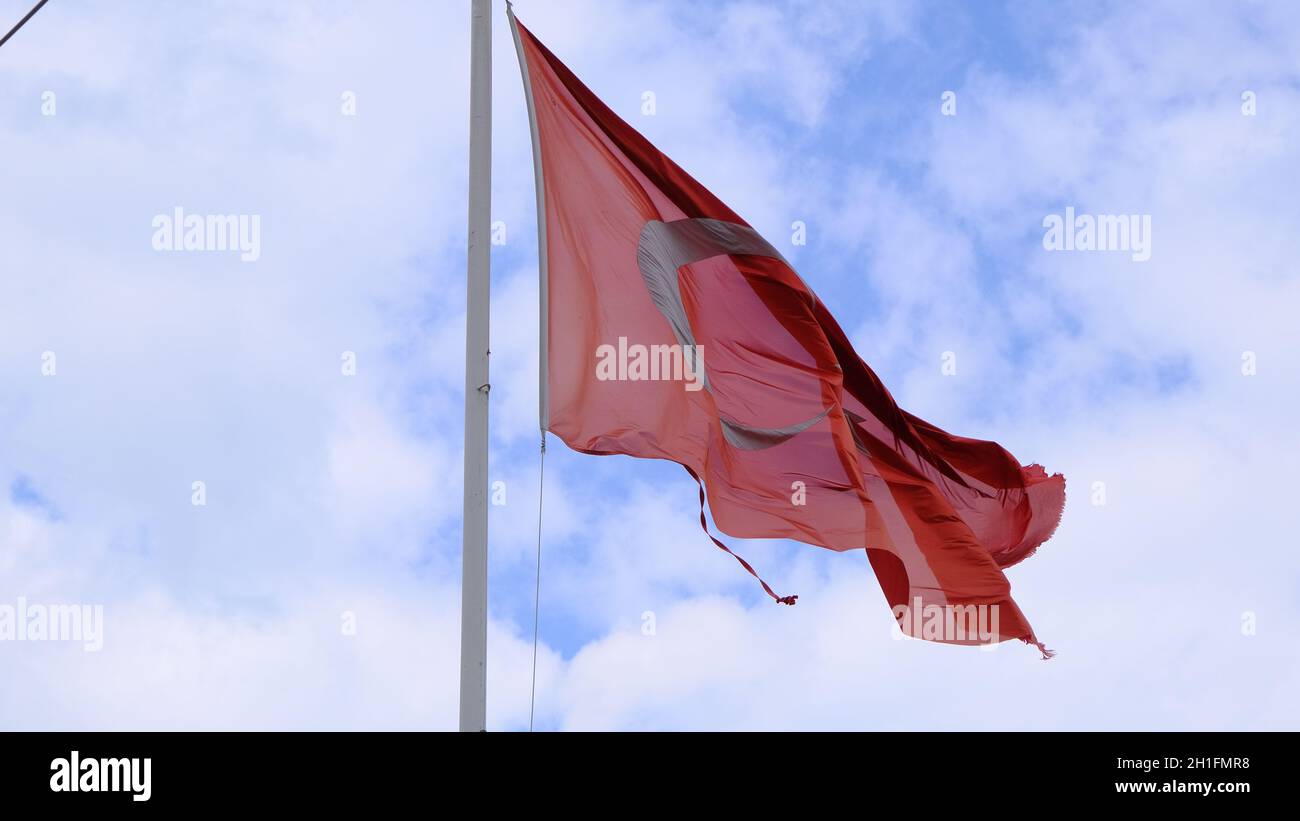 Riesige türkische Flagge mit bewölktem, wolkenbedecktem Himmel Hintergrund. Die Flagge ist zerriert Stockfoto