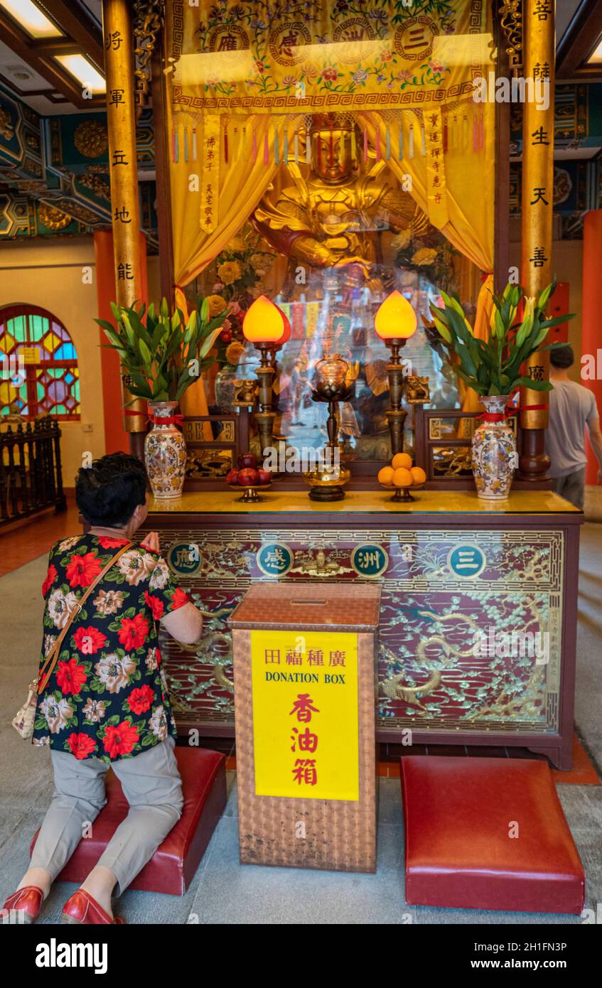 Eine Frau, die auf den Knien zu einer buddhistischen Statue im Kloster Po Lin auf der Insel Lantau in Hongkong betet Stockfoto