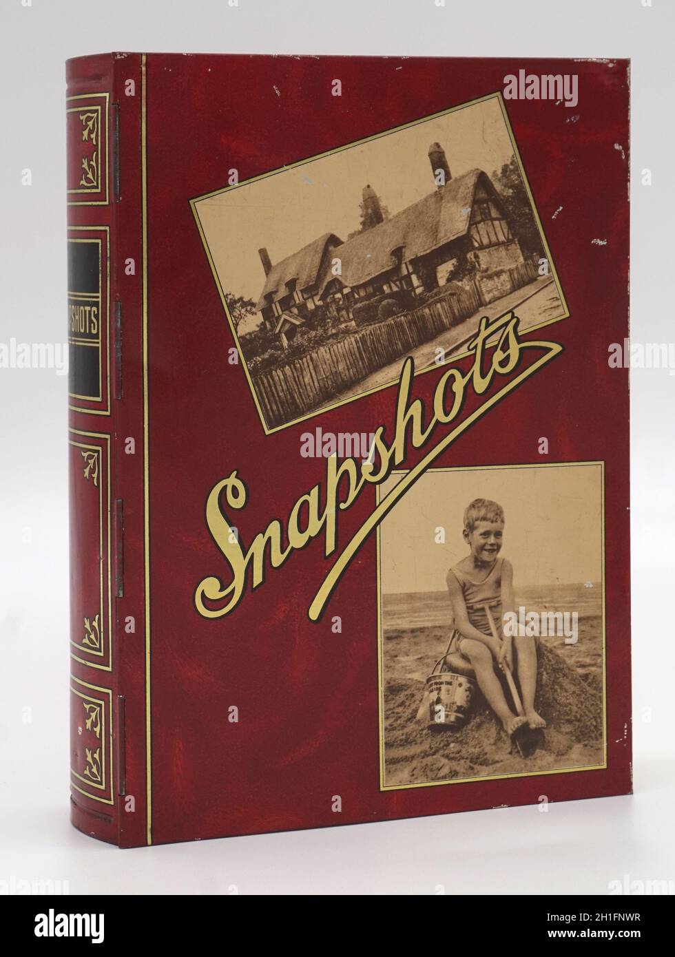 Schnappschüsse, bedruckte Metallbox für Fotos mit Klappdeckel. 1930er Jahre. Foto von reetgedeckten Häuschen und von Jungen auf Sandburg mit Eimer und Spaten. Britisch, Hersteller unbekannt. Stockfoto