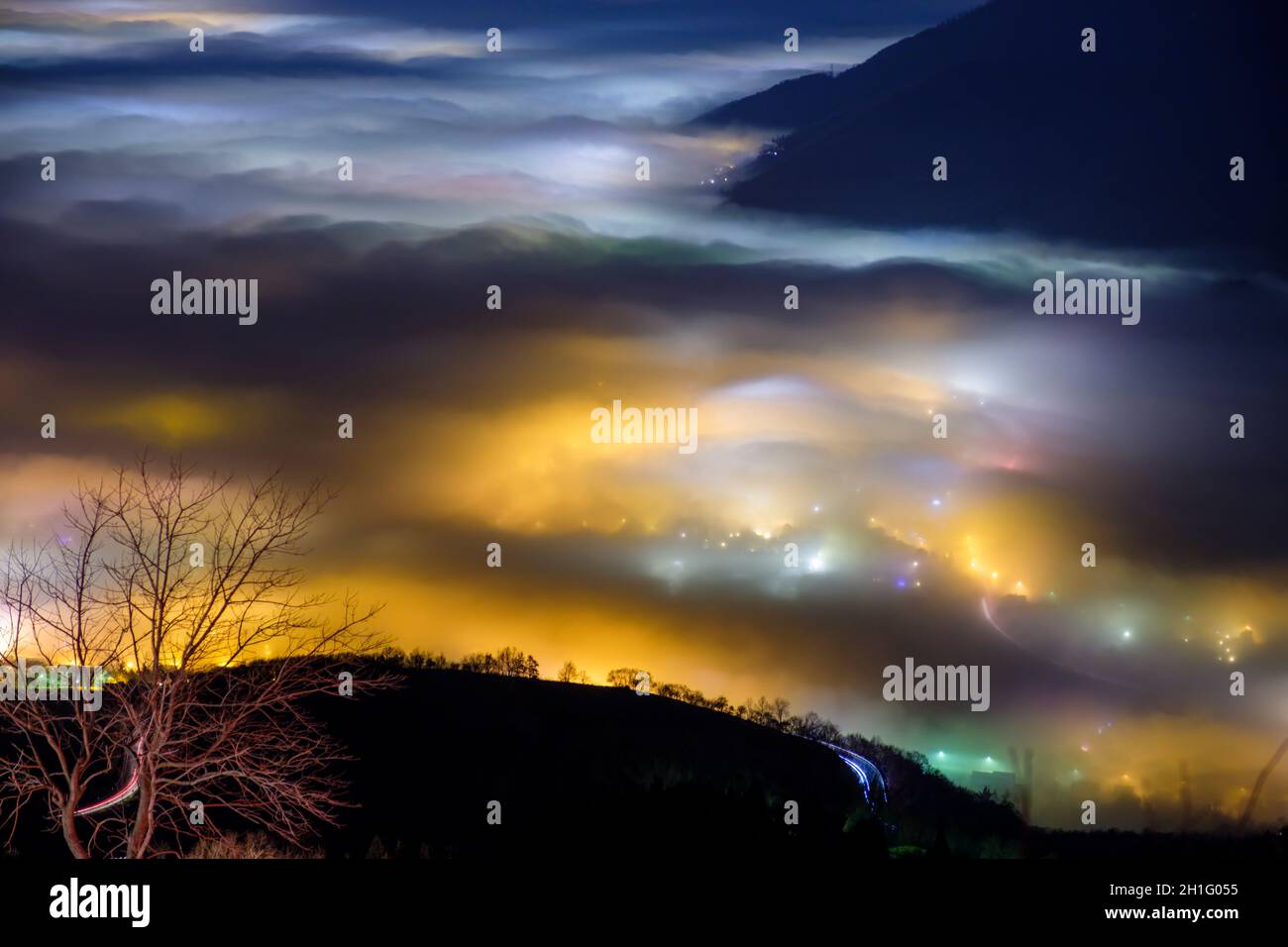 Blick von oben auf den dichten Nebel, der von den Nachtlichtern der Dörfer, der Po-Ebene, Provinz Vicenza, Italien, gefärbt wird Stockfoto