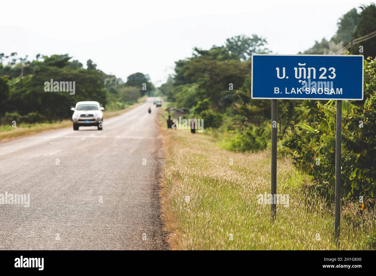 Ein Richtungsschild auf der Nationalstraße T 16 in Laos, B. Lak Saosam 23 nach Pakse von Salavan, nahe der vietnamesischen Grenze. Konzentrieren Sie sich auf das Schild. Stockfoto