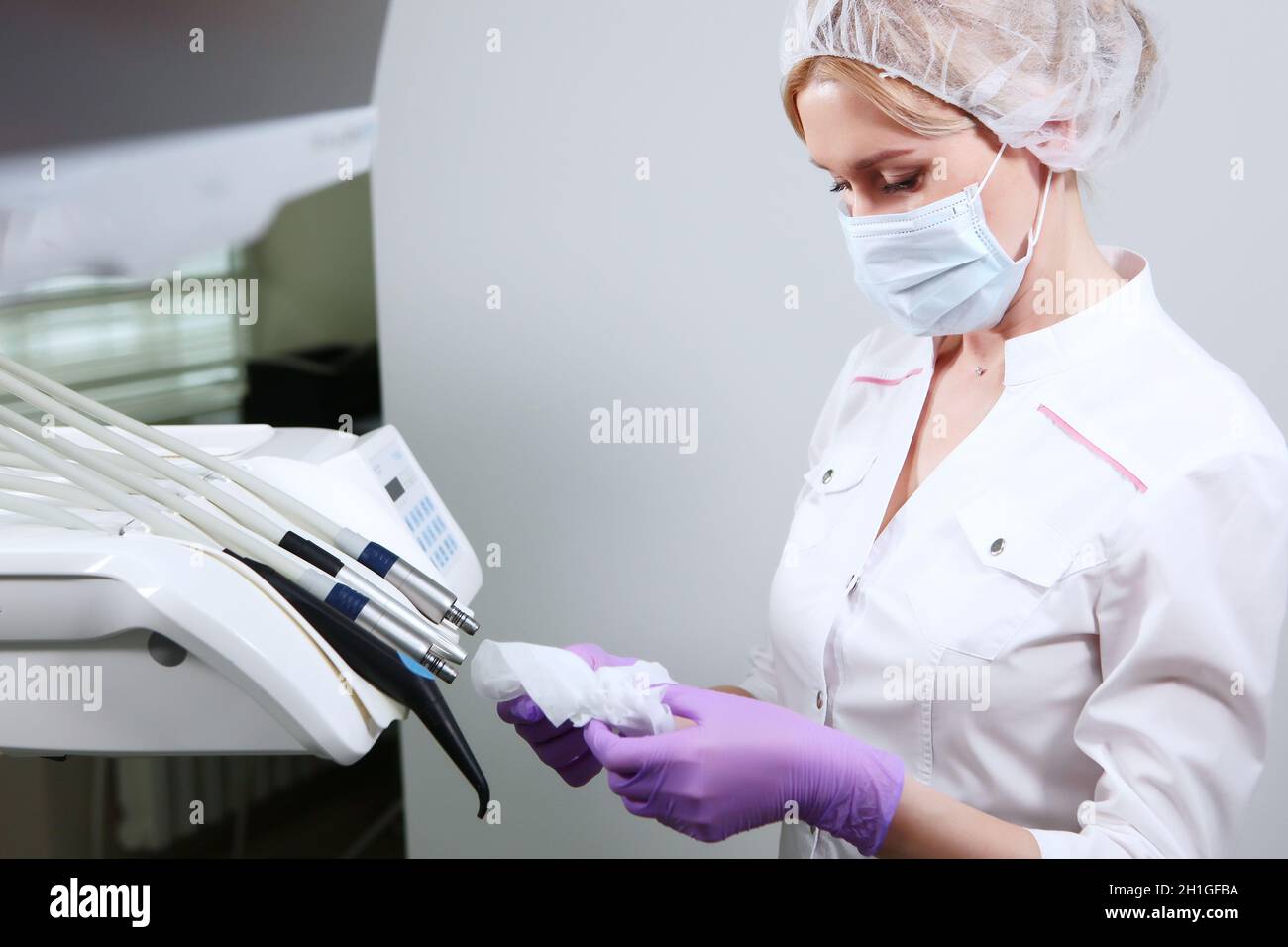 Eine Krankenschwester in Uniform und eine medizinische Maske wischt zahnärztliche Instrumente. Desinfektion in der Zahnarztpraxis. Speicherplatz kopieren. Stockfoto