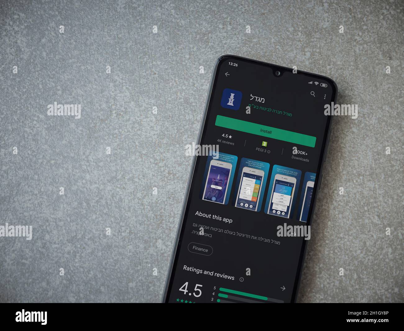 LOD, Israel - 8. Juli 2020: Migdal App Play Store-Seite auf dem Display eines schwarzen mobilen Smartphones auf Keramikstein Hintergrund. Draufsicht flach liegend mit Stockfoto