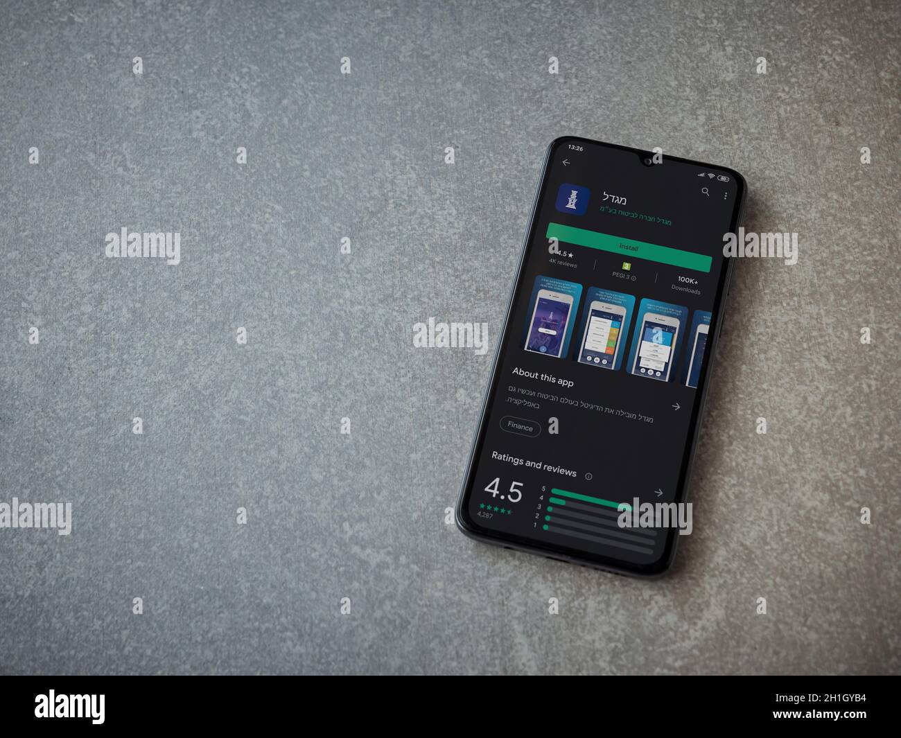 LOD, Israel - 8. Juli 2020: Migdal App Play Store-Seite auf dem Display eines schwarzen mobilen Smartphones auf Keramikstein Hintergrund. Draufsicht flach liegend mit Stockfoto