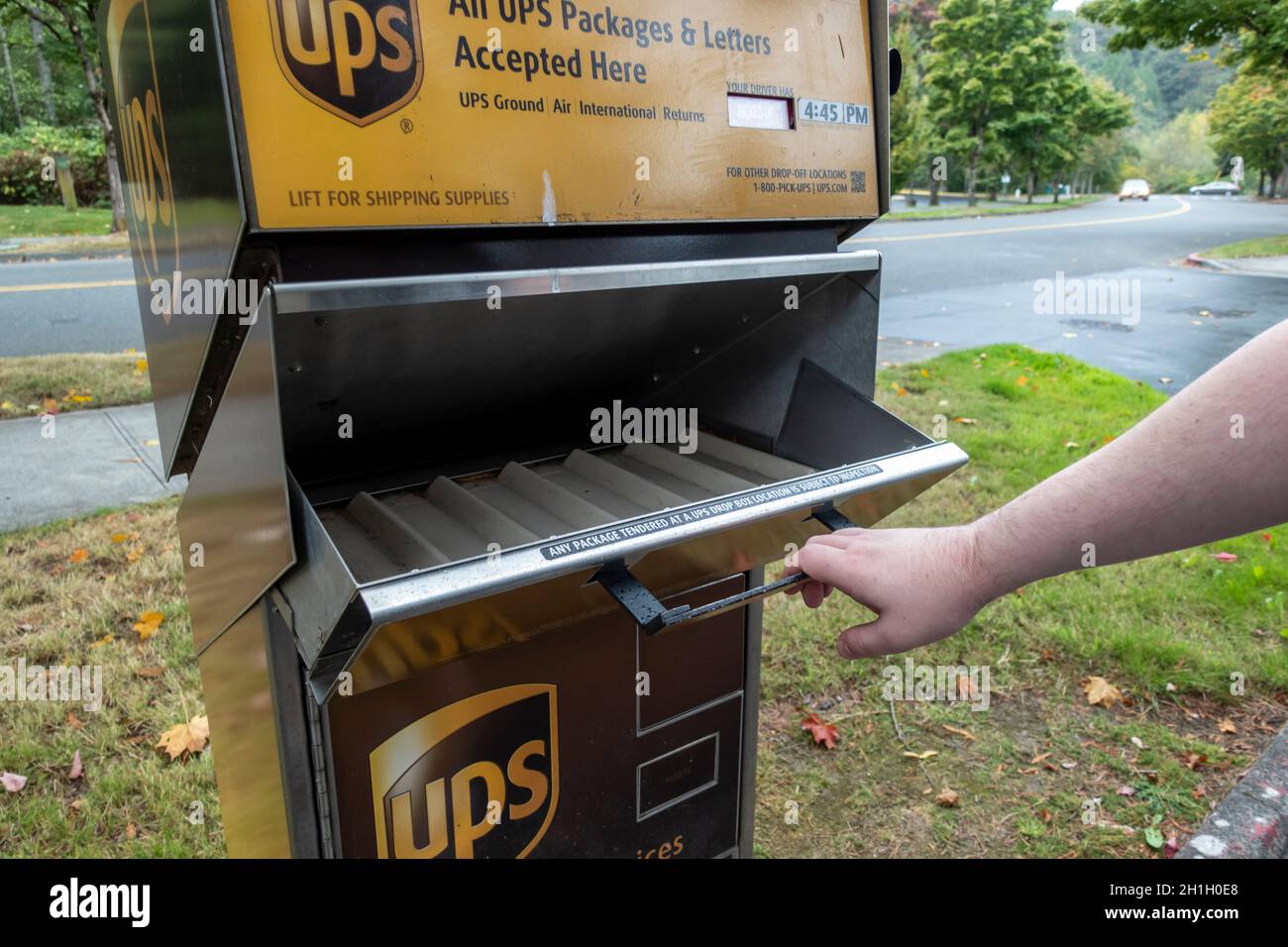 Kirkland, WA USA - ca. September 2021: Schräge Ansicht einer Hand, die ein UPS-Paket und eine Brieflagerstation in der Innenstadt von Kirkland aufzieht. Stockfoto