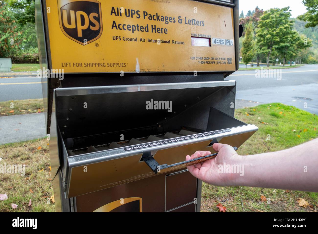 Kirkland, WA USA - ca. September 2021: Schräge Ansicht einer Hand, die ein UPS-Paket und eine Brieflagerstation in der Innenstadt von Kirkland aufzieht Stockfoto