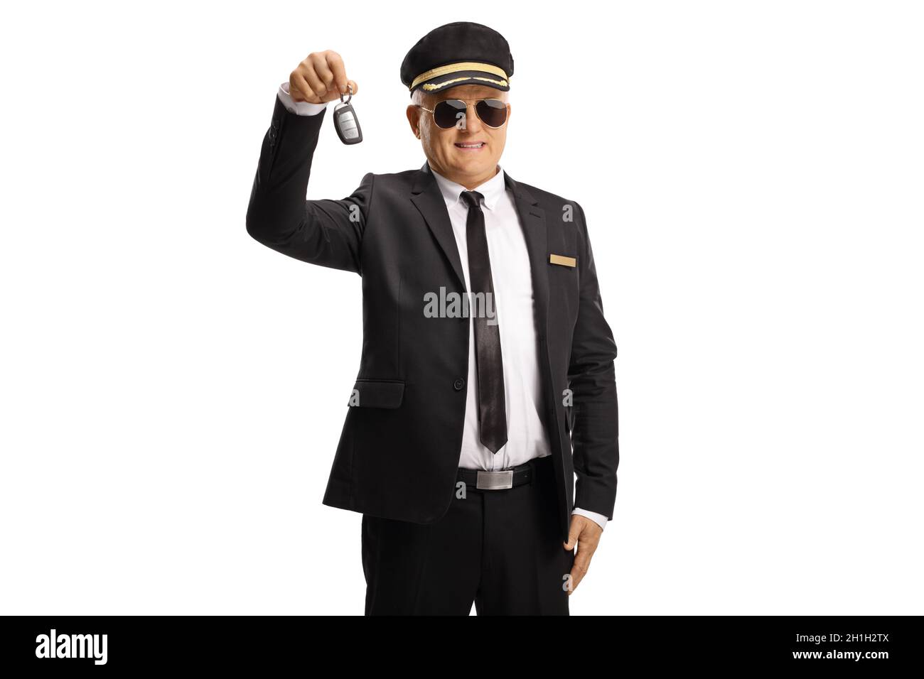 Chauffeur in einer Uniform mit Sonnenbrille, die einen auf weißem Hintergrund isolierten Autoschlüssel hält Stockfoto