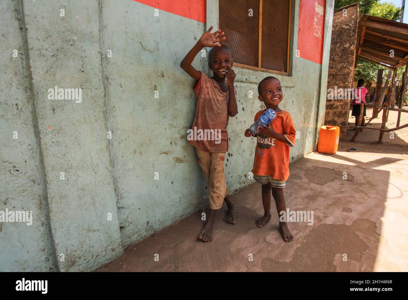 Malindi, Kenia - April 06, 2015: Zwei unbekannte kleine Jungen, neben Wand, lächelnd und winkend auf die touristischen Besuch der lokalen Slum. Viele Kinder suff Stockfoto