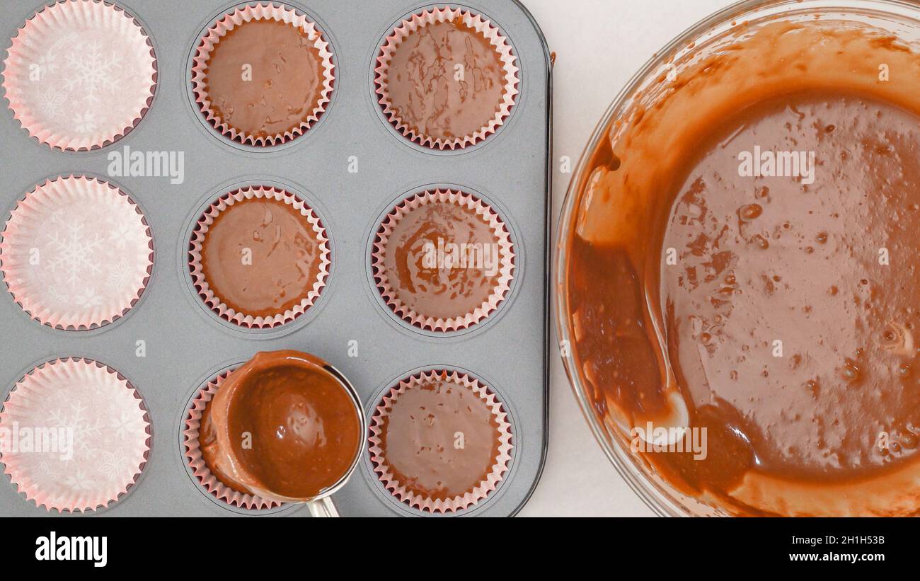 Schaufeln des Schokoladenkuchen-Teigs in eine ausgekleidete Cupcake-Pfanne. Schritt für Schritt Schokolade Muffins Rezept, Backprozess Stockfoto