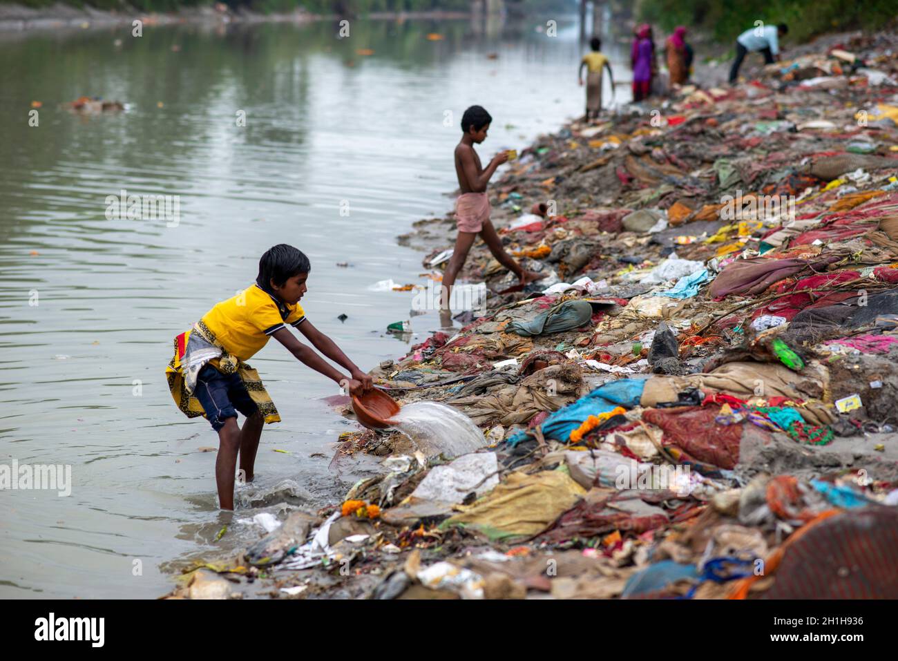 Muradnagar, Indien. Oktober 2021. Ein Kind wirft Wasser auf ihre gesammelten wertvollen Gegenstände aus den Abfallhaufen am Ufer des Ganges-Kanals in Muradnagar.Einheimische suchen im Oberen Ganges-Kanal, der von schweren Bächen am Ufer des Kanals aufgetürmt wird, gerne nach wertvollen Gegenständen. Eifrige Anhänger bieten während eines Tauchgangs im Ganga-Kanal Wertsachen als religiöse Praxis an oder verlieren sie dort unwissentlich. Kredit: SOPA Images Limited/Alamy Live Nachrichten Stockfoto