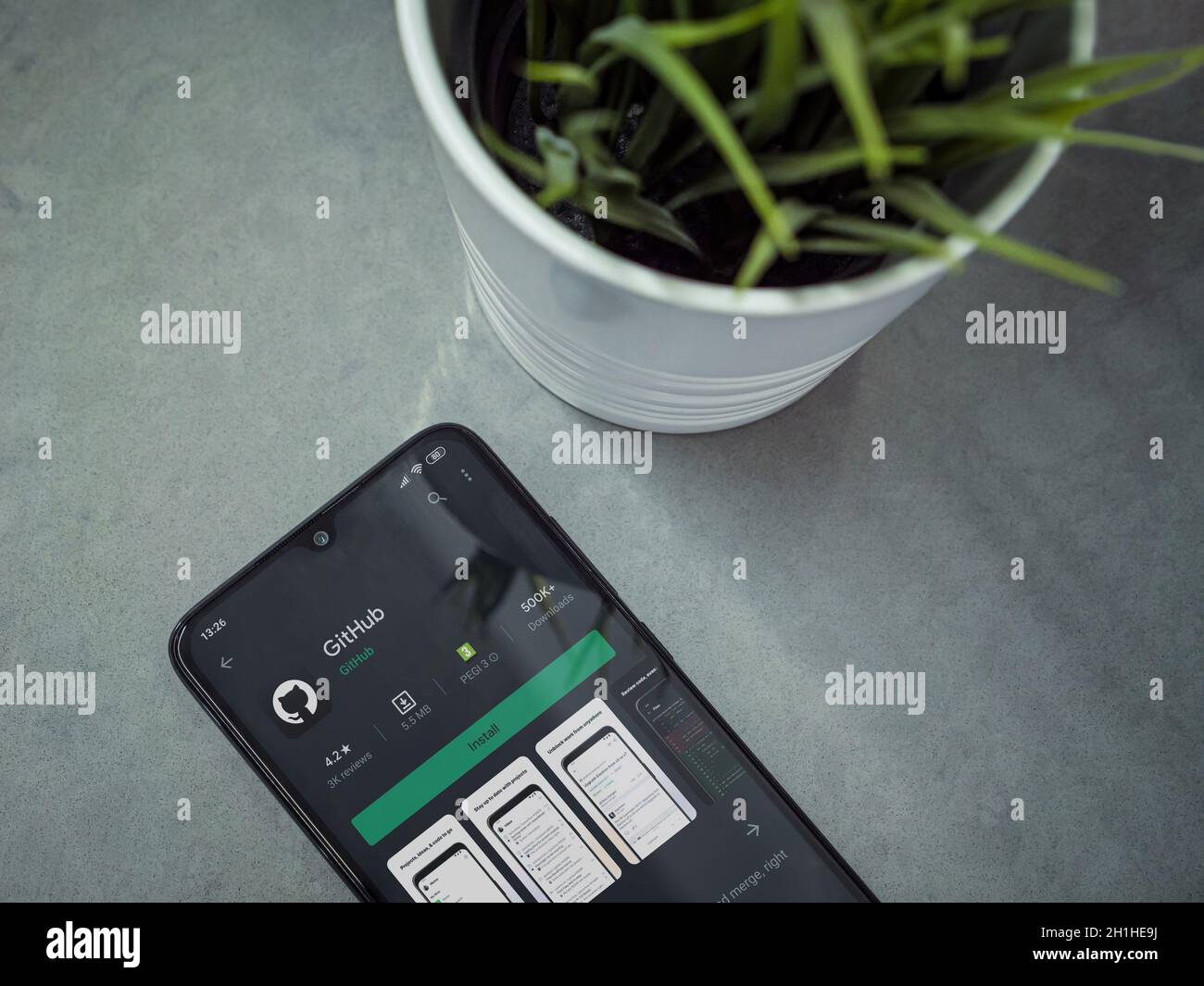 LOD, Israel - 8. Juli 2020: Moderner minimalistischer Büroarbeitsplatz mit schwarzem Smartphone mit GitHub App Play Store Seite auf Marmor Hintergrund. Oben Stockfoto