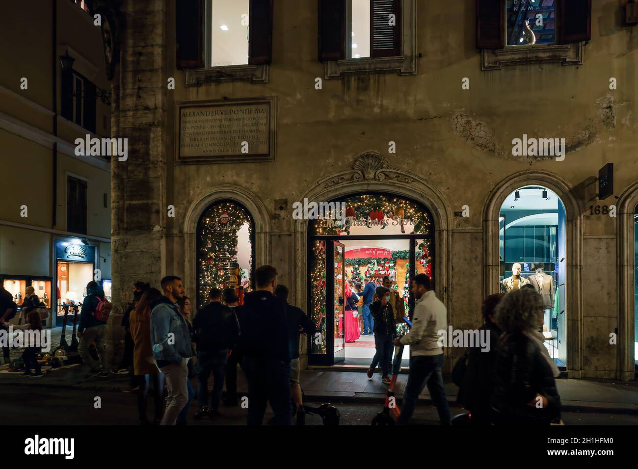 Rom, Italien die Schaufensterdekoration im Weihnachtsgeschäft mit festlichen Dekorationen. Beleuchtete Nachtansicht des saisonalen Geschäfts mit Menschenmassen in der Via del Corso in der römischen Hauptstadt. Stockfoto