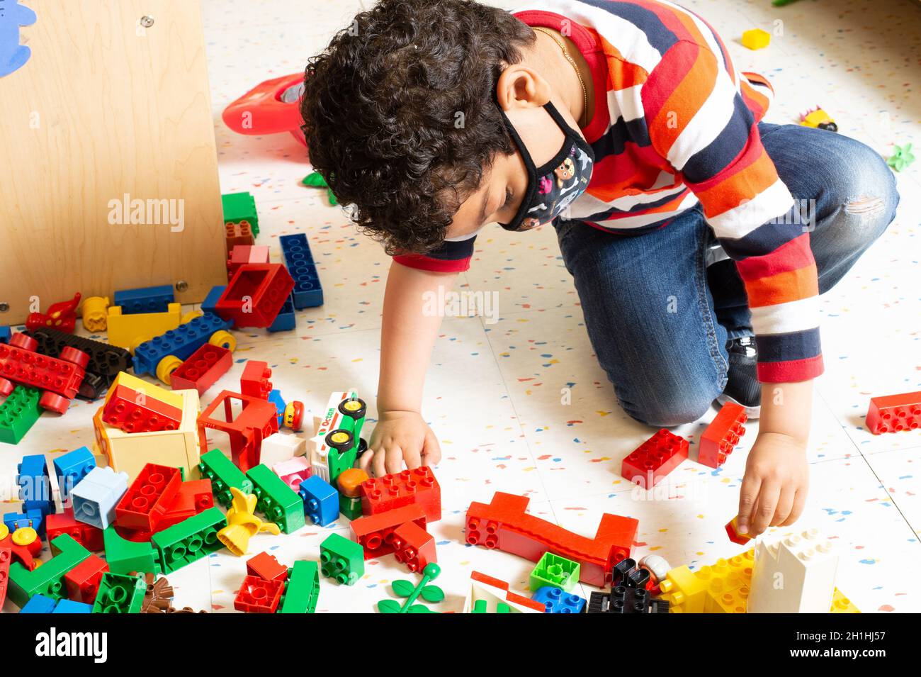 Bildung Vorschule 4-5-Jährige Junge spielt allein mit verbindenden Plastikziegeln (Duplo) Stockfoto