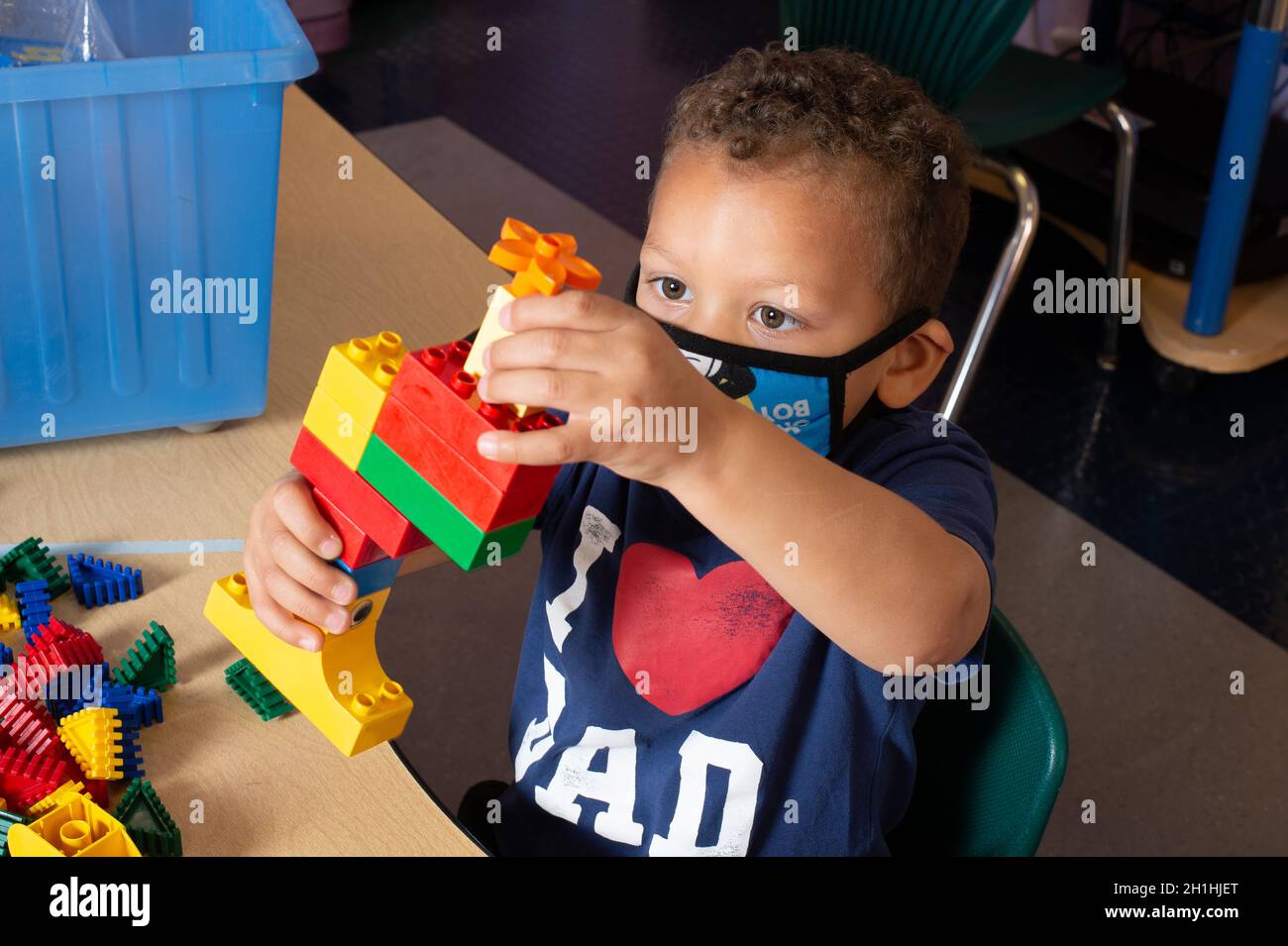 Bildung Vorschule 3-4 Jahre alt Junge spielt allein Gebäude mit bunten Plastikziegeln (Duplo) Stockfoto